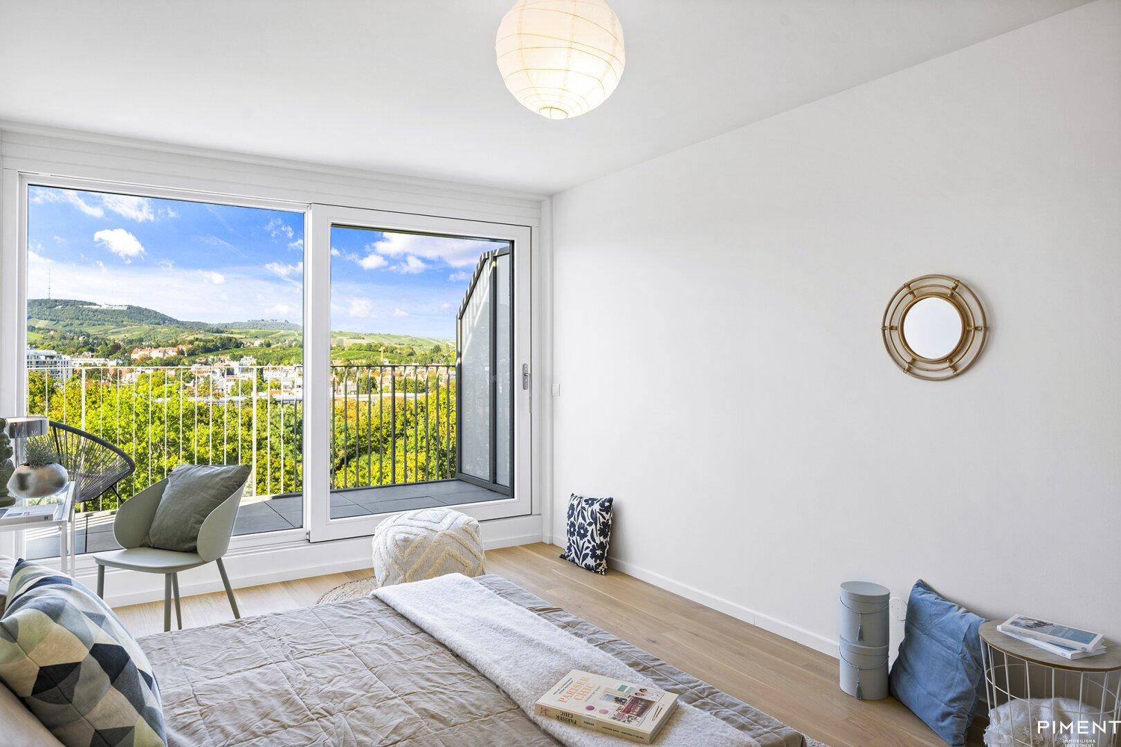 Schlafzimmer mit Balkonzugang, Holzboden und weitem Blick auf die Landschaft.