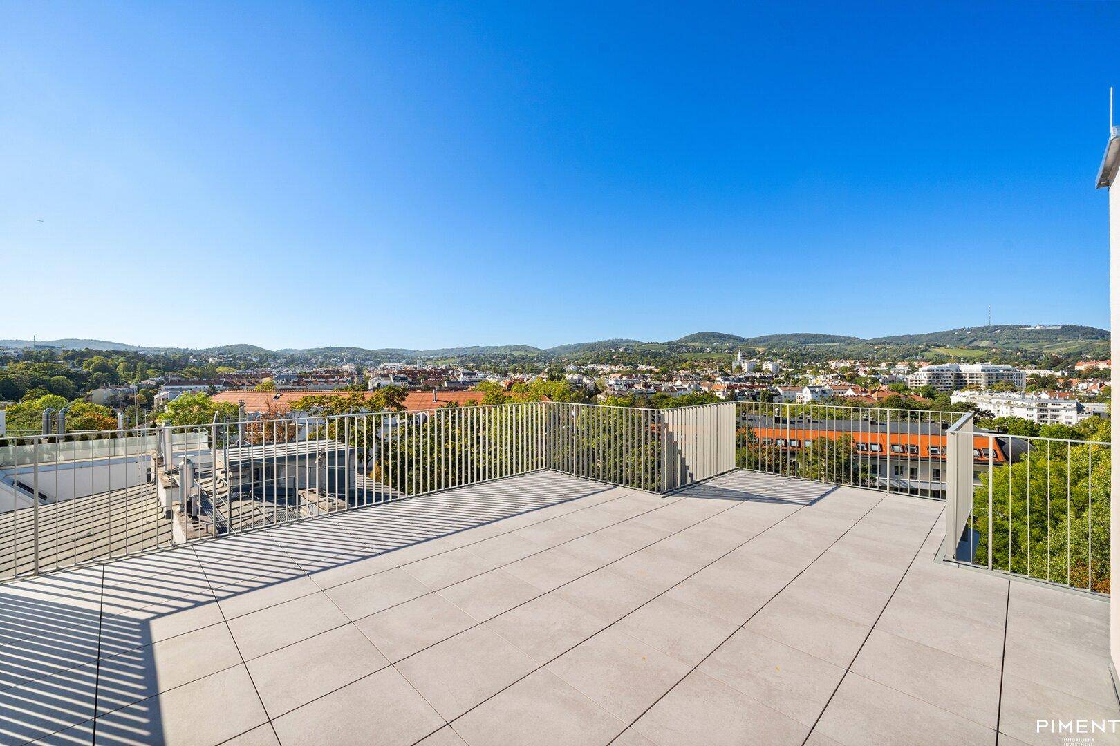 Große Dachterrasse mit Fliesenboden und weitem Panoramablick über die Stadt und Umgebung.