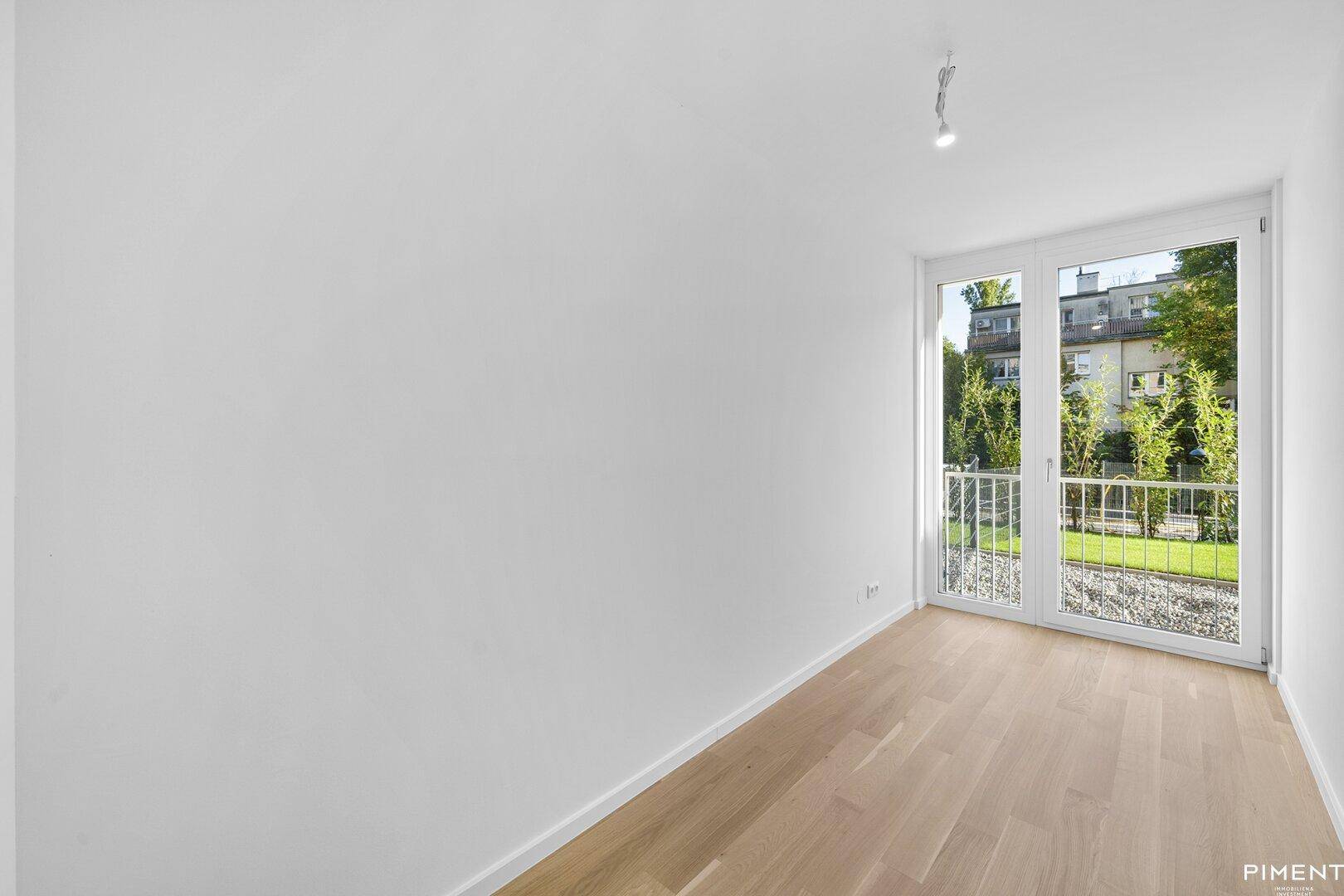 Kleineres Zimmer mit Holzboden und Fenstertür zu einem französischen Balkon.