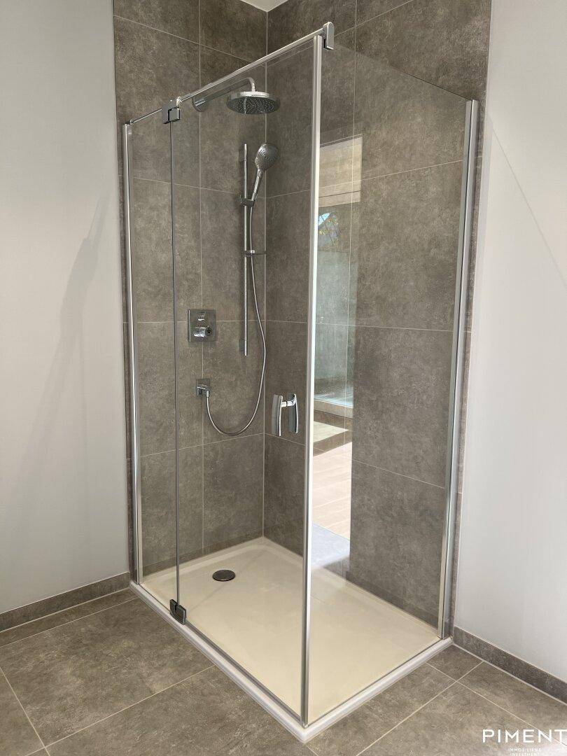 Geräumige, moderne Duschkabine mit Glaswänden und Regenduschkopf im Badezimmer.