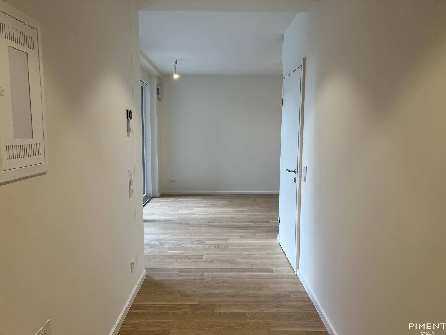Langer, heller Flur mit Parkettboden, der verschiedene Räume der Wohnung verbindet.