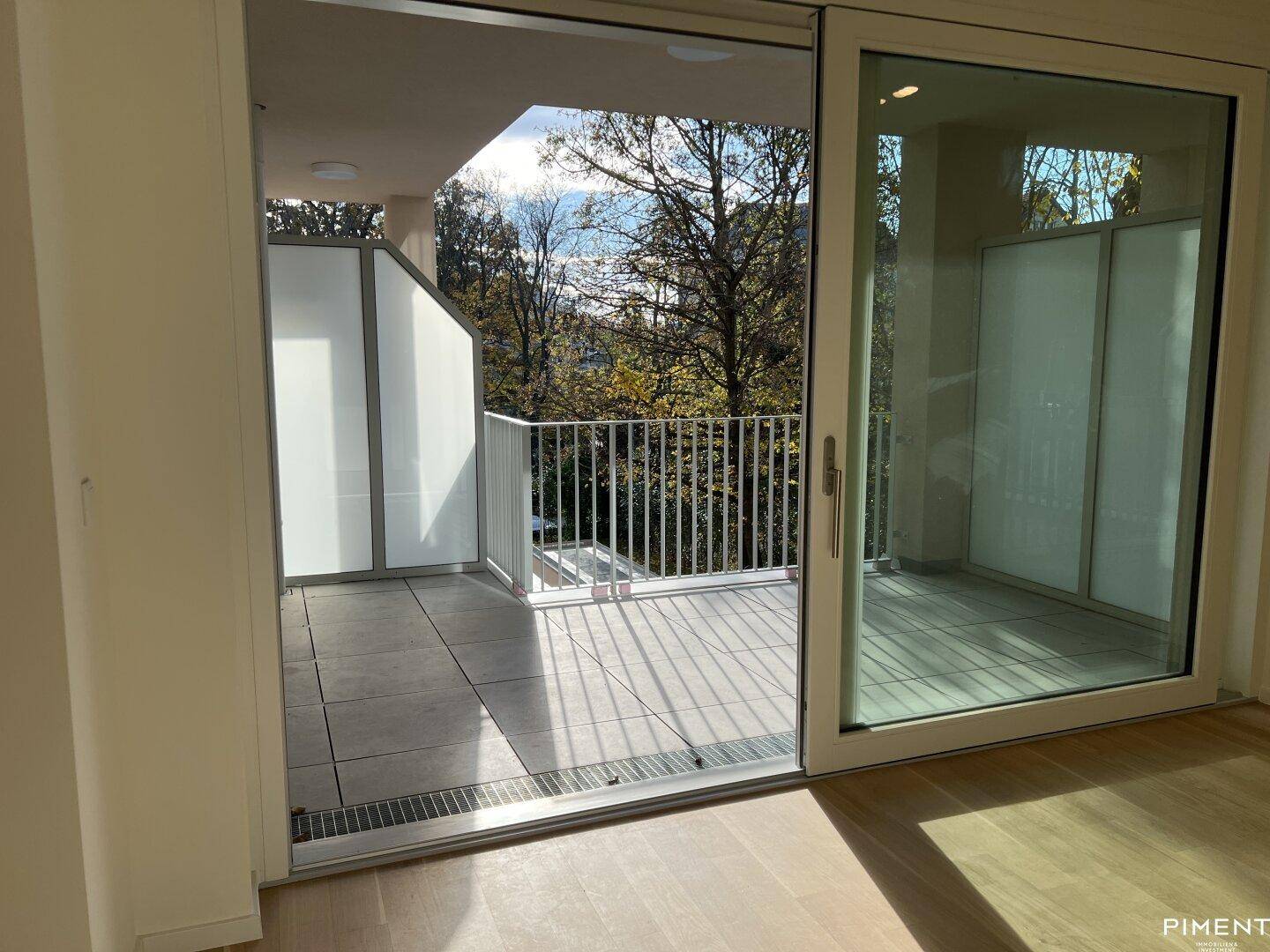 Heller Raum mit Parkettboden und großem Schiebetürzugang zu einem geräumigen Balkon.