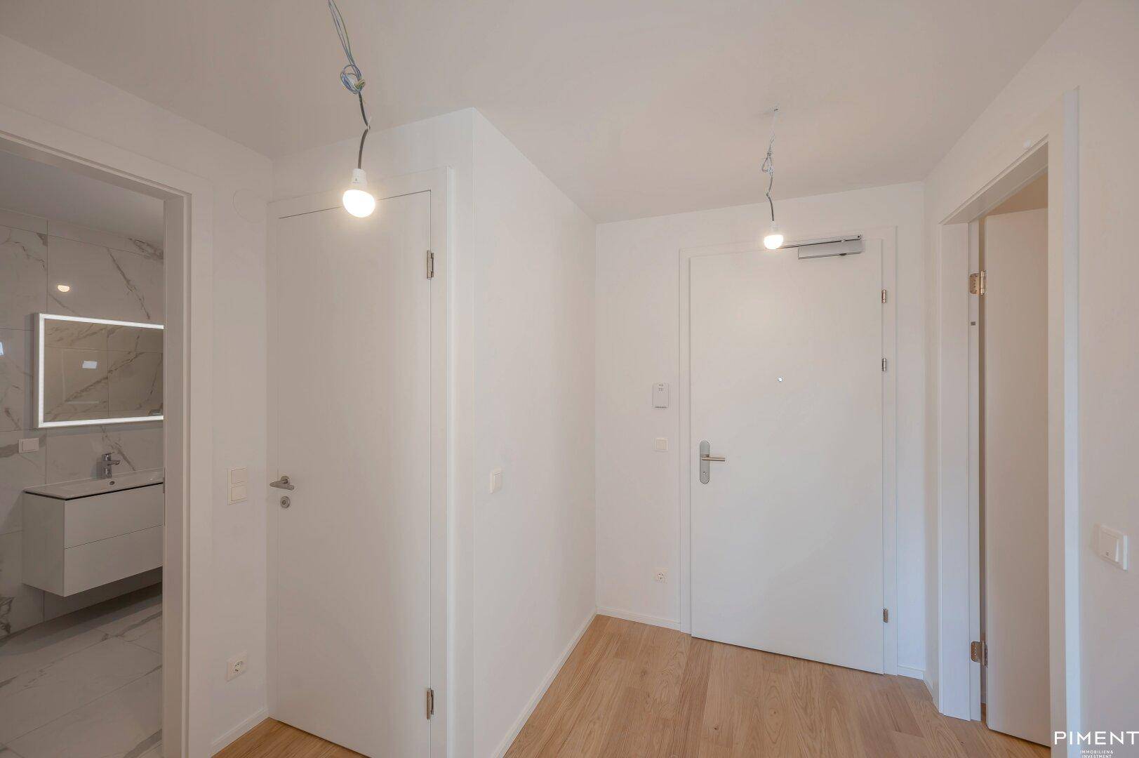 Heller Flur mit Parkettboden und weißen Türen, der Zugang zu verschiedenen Räumen der Wohnung bietet.