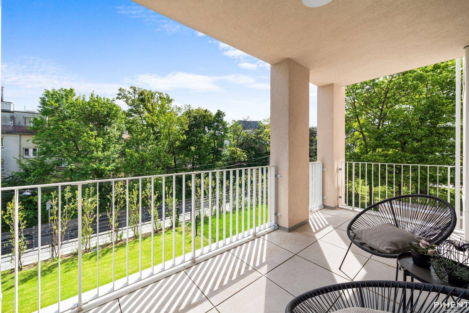 Geräumiger Balkon mit modernen Outdoor-Sesseln und einem schönen Blick ins Grüne.
