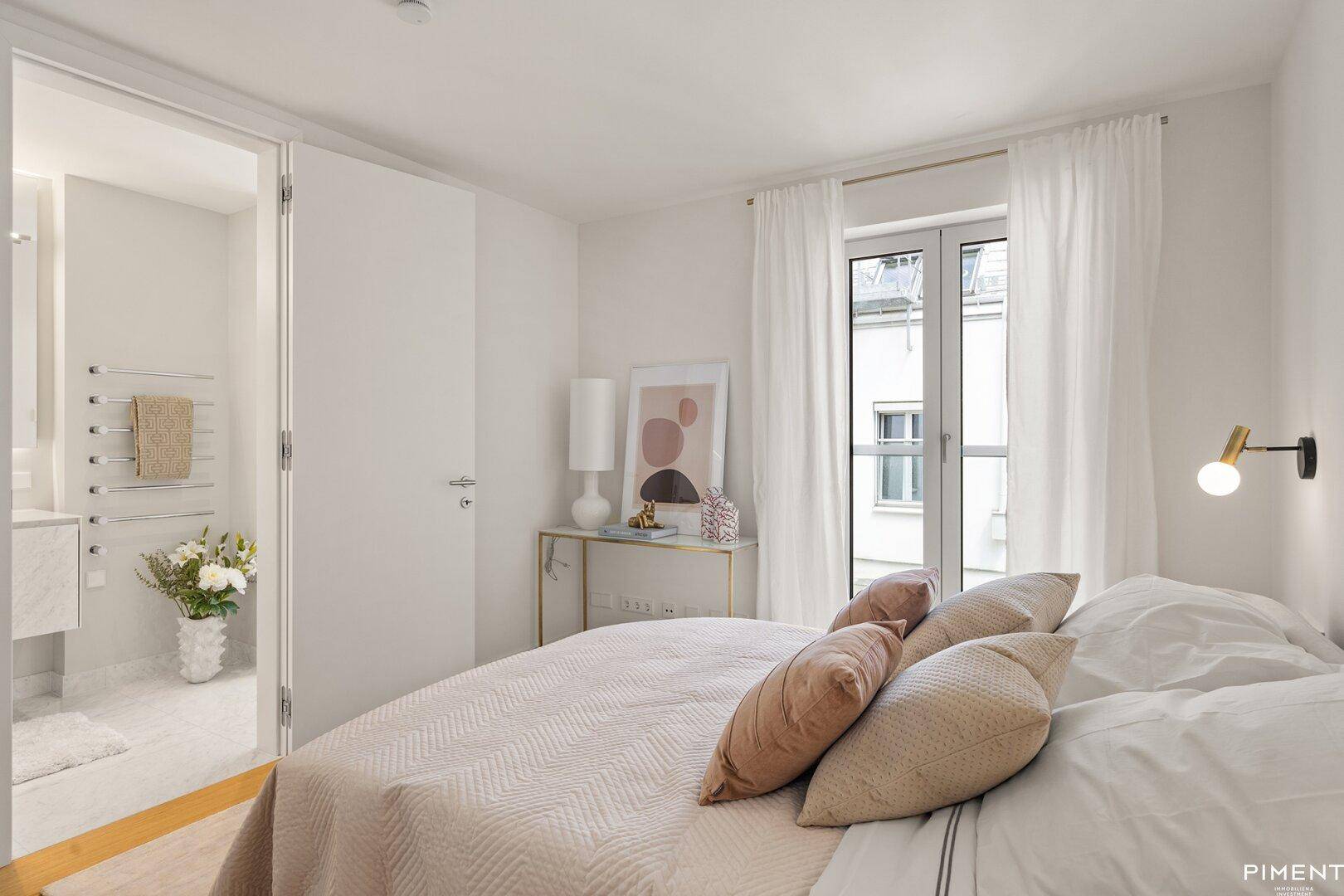 Helles Schlafzimmer mit Zugang zu einem modernen Bad und stilvoller Einrichtung.