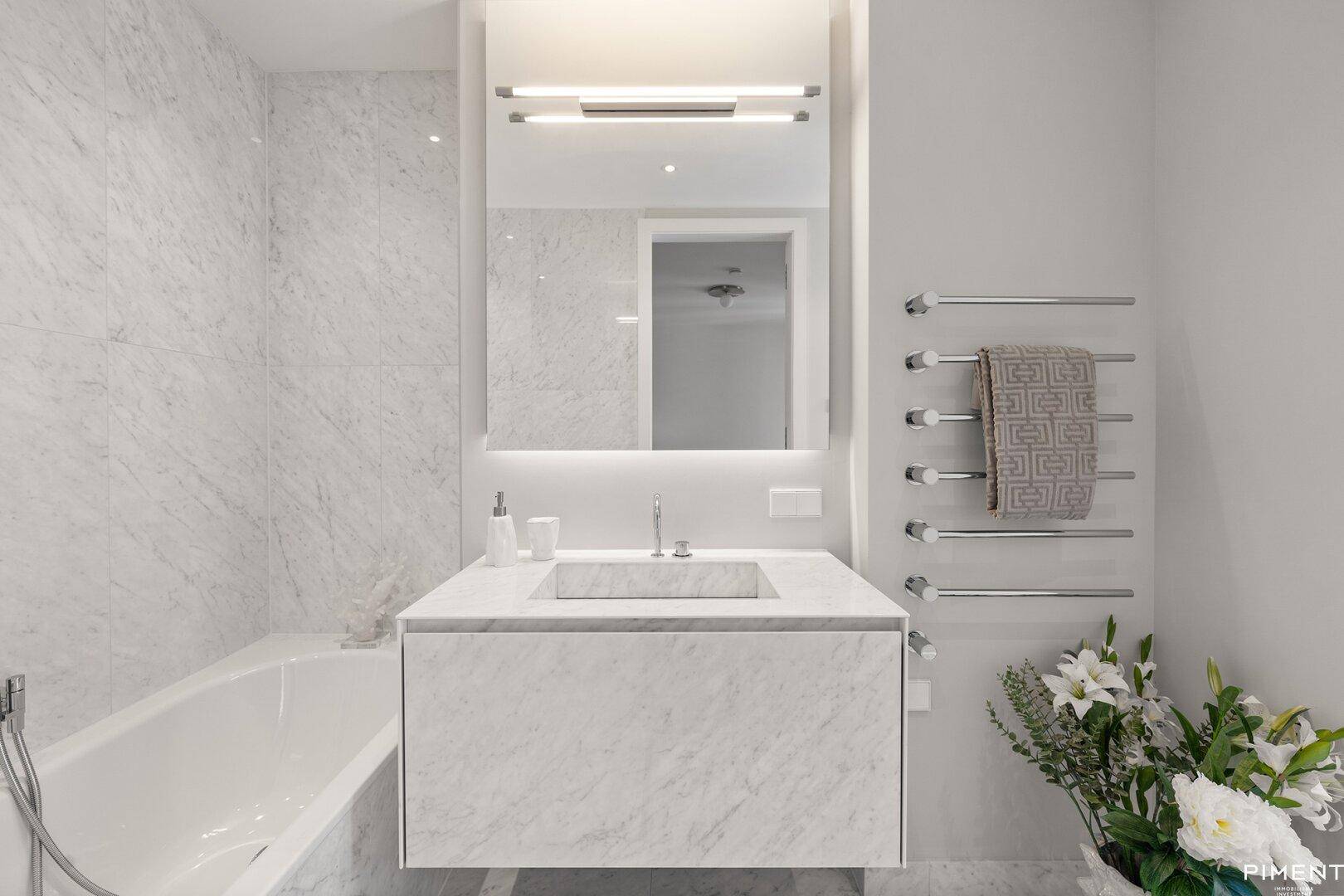 Stilvolles Badezimmer mit Badewanne, Marmorwaschtisch und beheiztem Handtuchhalter.