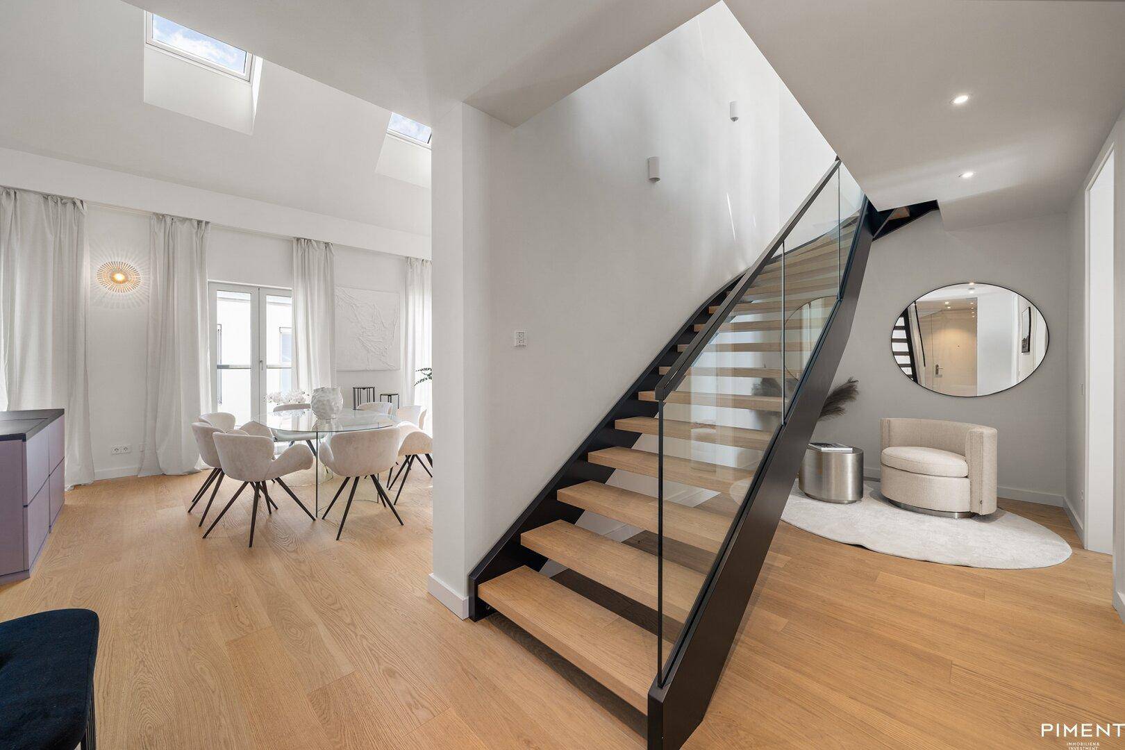 Elegante moderne Treppe mit Glasgeländer, die den Wohnbereich mit den oberen Etagen verbindet.