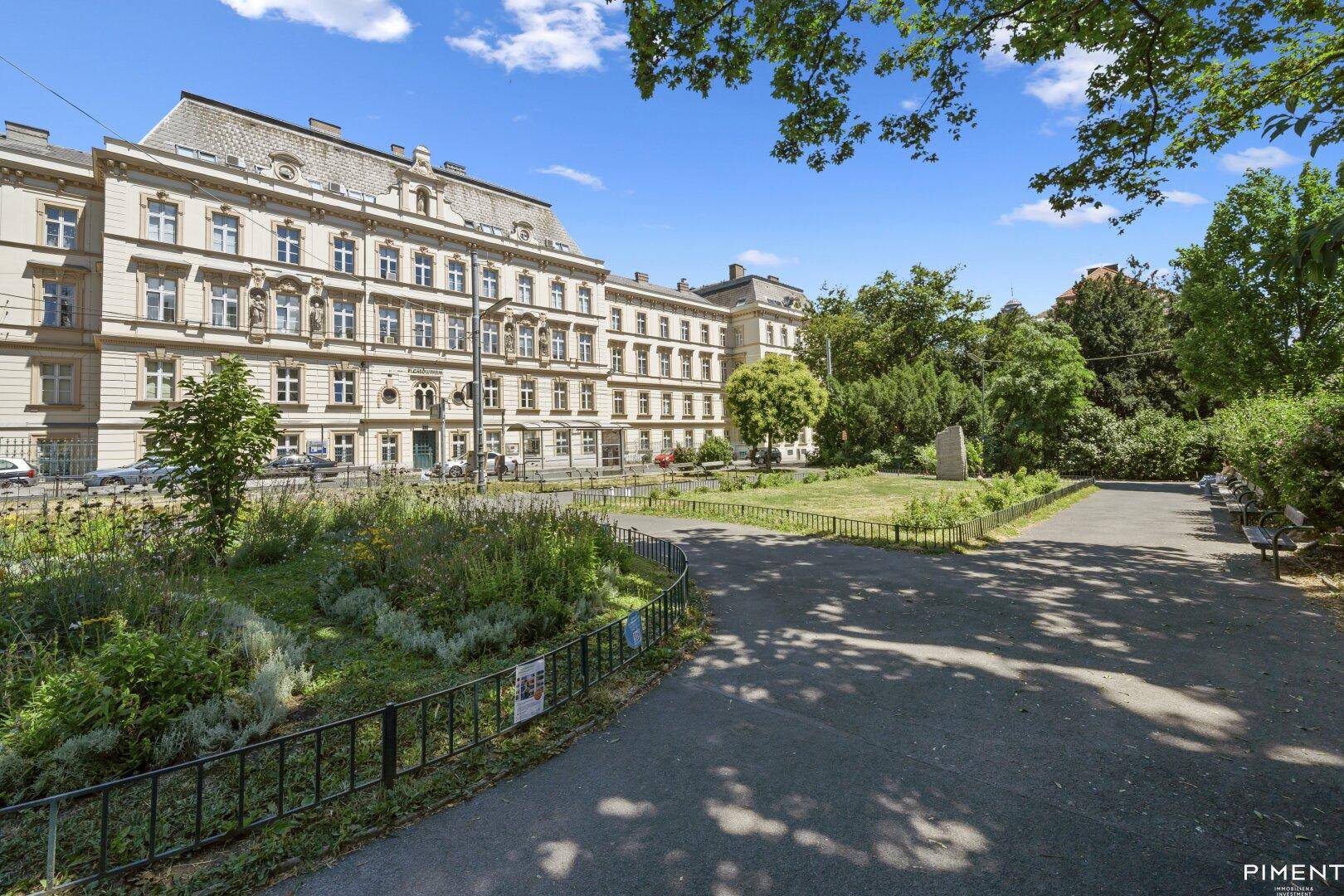 Elegantes Gebäude mit klassischer Architektur, das an einen weitläufigen, grünen Park grenzt.