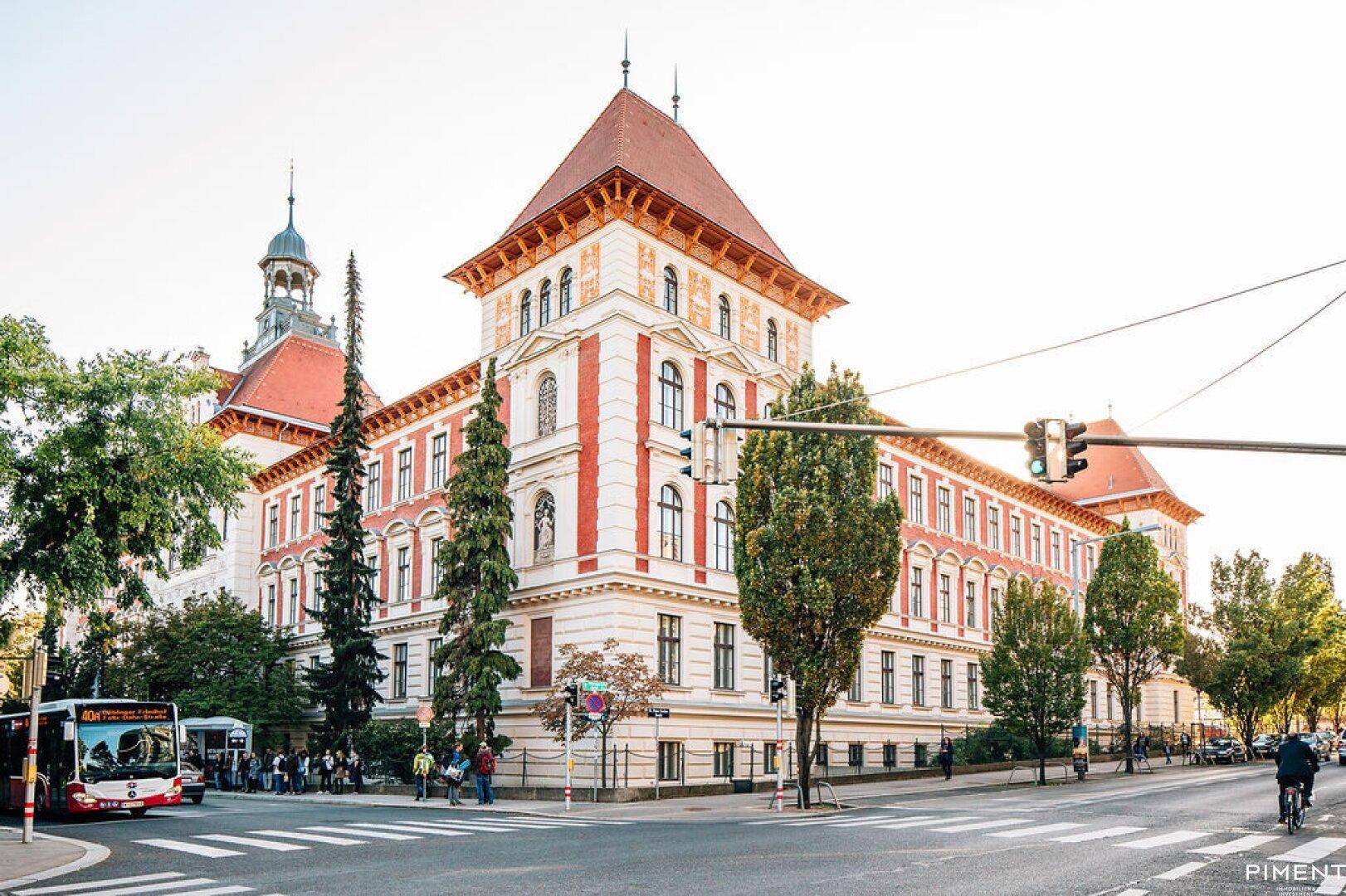 Prächtiges historisches Gebäude mit rotem Dach und markanter Architektur an einer belebten Kreuzung.