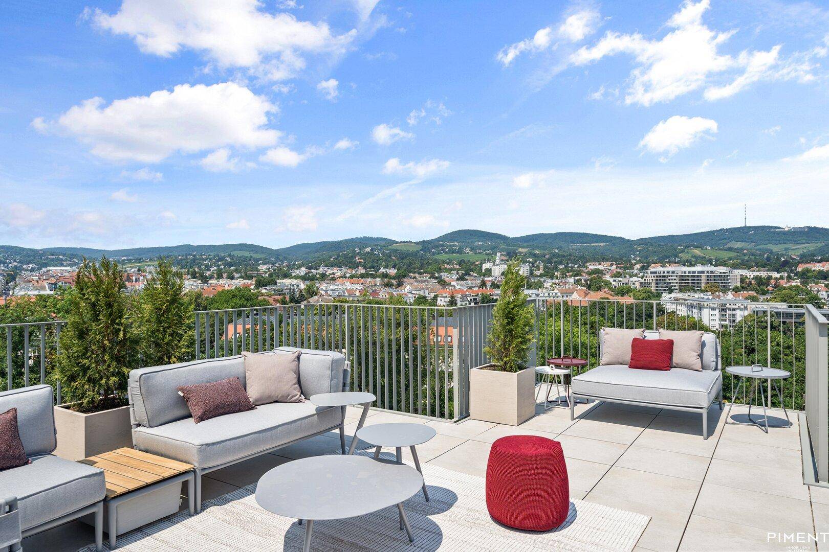 Geräumige Dachterrasse mit modernen Lounge-Möbeln und weitem Blick über die Stadt und grüne Hügel.