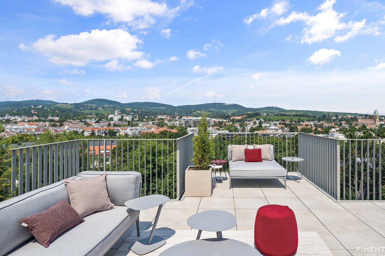 Moderne Dachterrasse mit bequemen Loungemöbeln und einem atemberaubenden Blick über die Stadt und grüne Hügel.