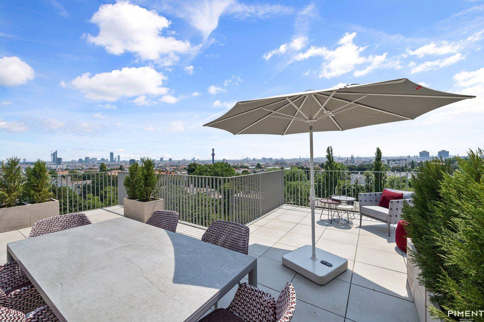 Großzügige Dachterrasse mit Esstisch, Sonnenschirm und beeindruckendem Ausblick auf die Stadt und die Ferne.