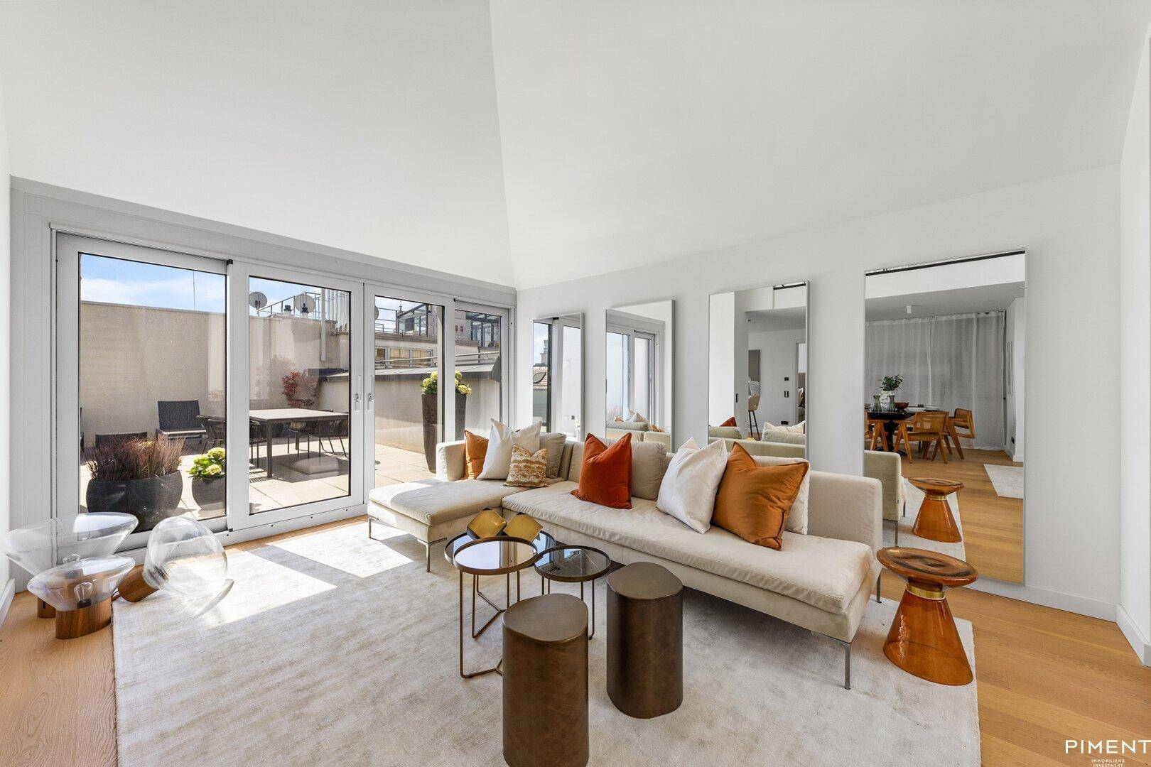 Gemütlicher Wohnbereich mit beigem Sofa, Holzboden und Zugang zu einer sonnigen Dachterrasse.