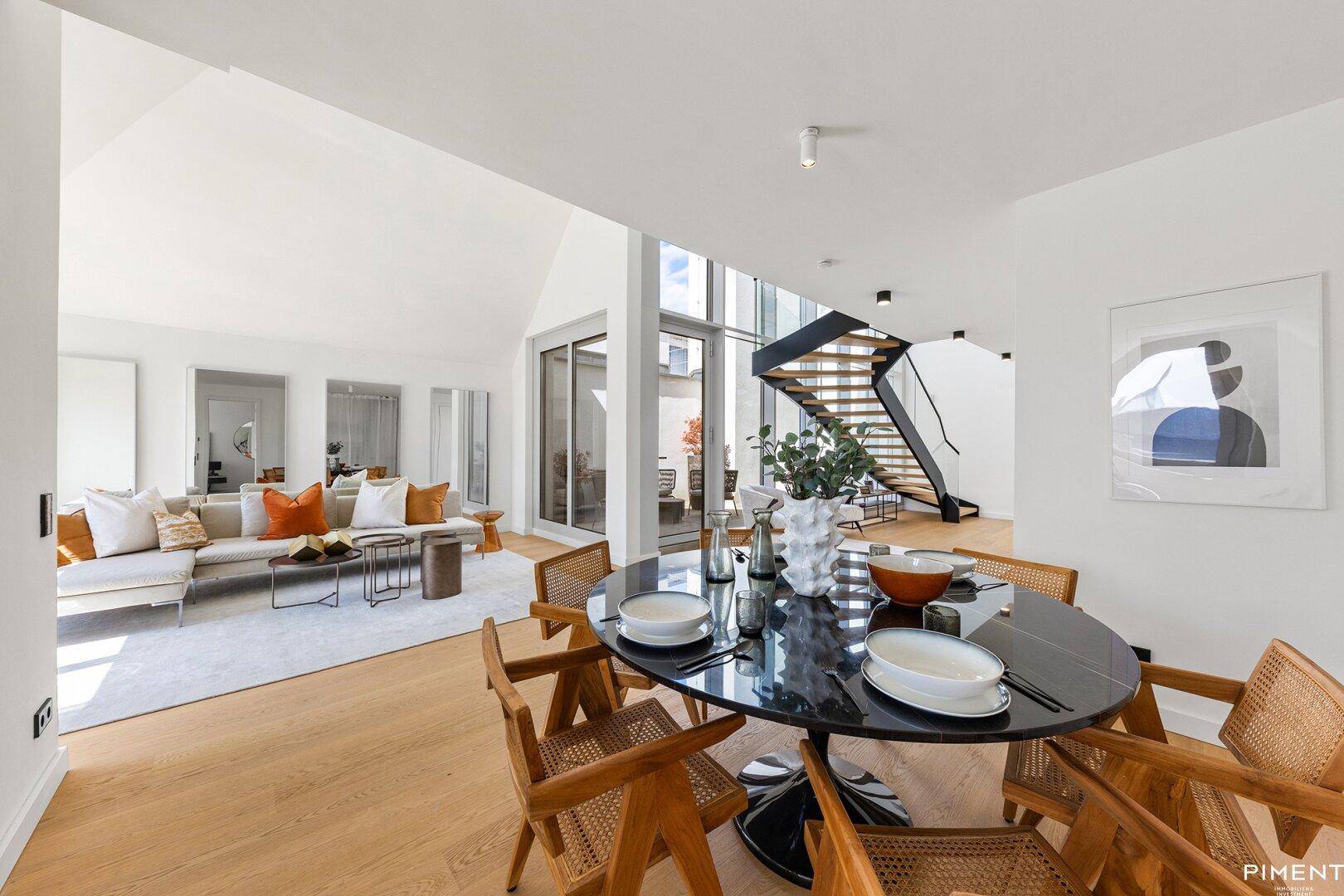 Eleganter Essbereich mit rundem Tisch und Blick auf den offenen Wohnbereich und die moderne Treppe.