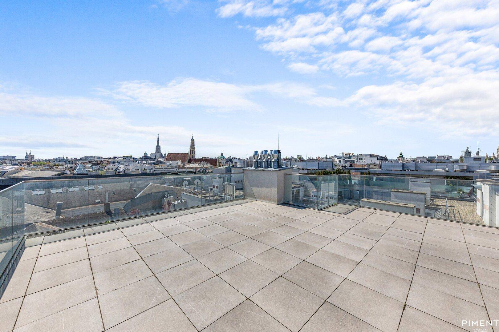 Weitläufige Dachterrasse mit Fliesenboden und Panoramablick über die Stadt.