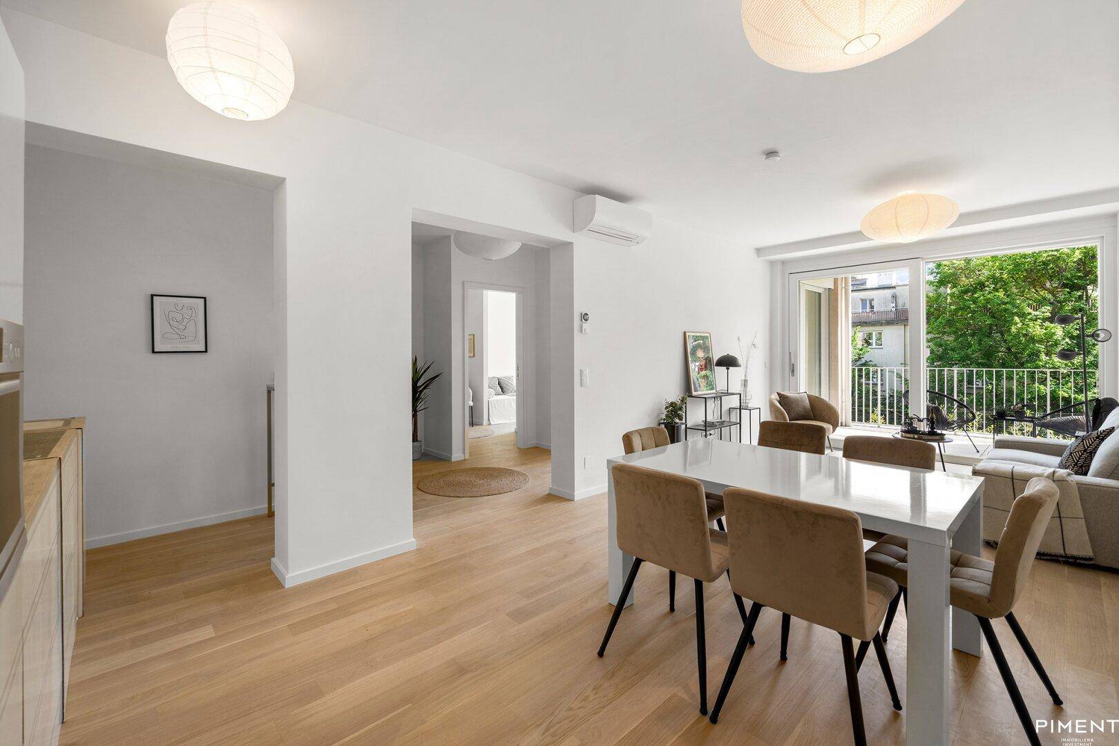 Heller, offener Wohn-Essbereich mit Holzboden und Zugang zum Balkon, modern eingerichtet.