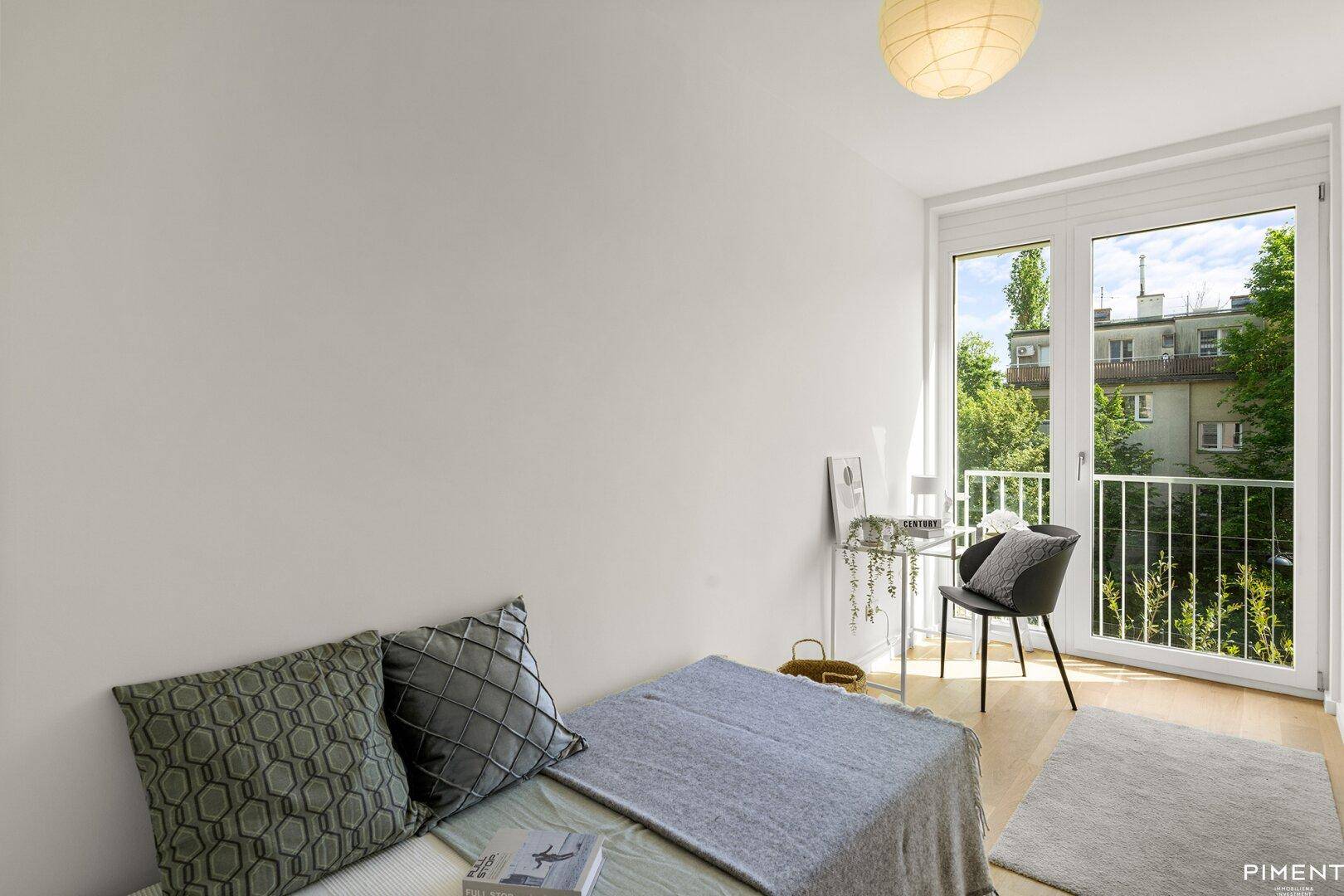 Gemütliches Schlafzimmer mit hellem Holzboden und großem Fenster mit Blick ins Grüne.