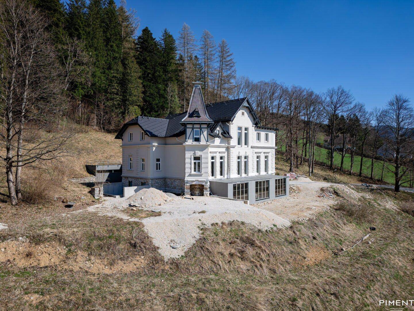 Freistehende Villa in Hanglage mit klassischer Architektur und moderner Glaserweiterung.