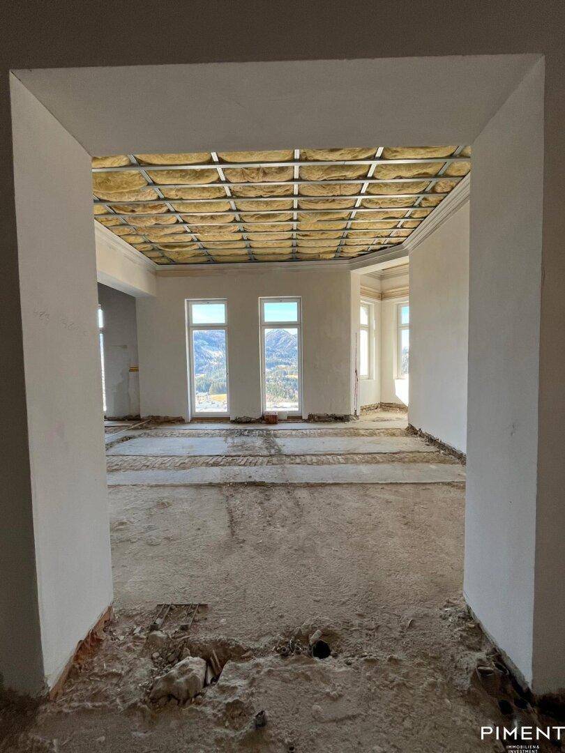 Langer Flur oder offener Bereich im Rohbau mit Blick auf die Berge.