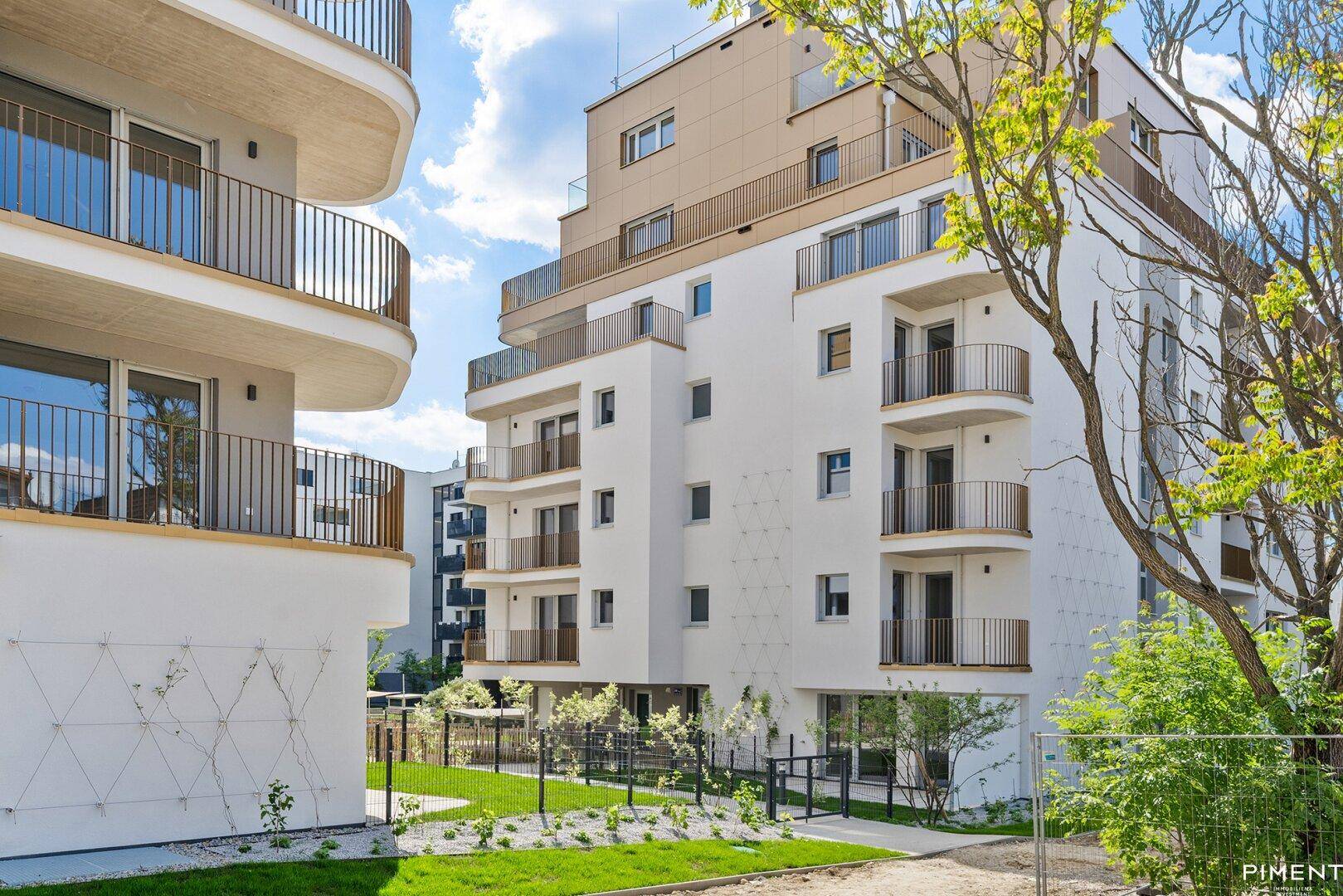 Moderne Wohngebäude mit weißen Fassaden, Balkonen und gepflegten Grünflächen im Außenbereich.