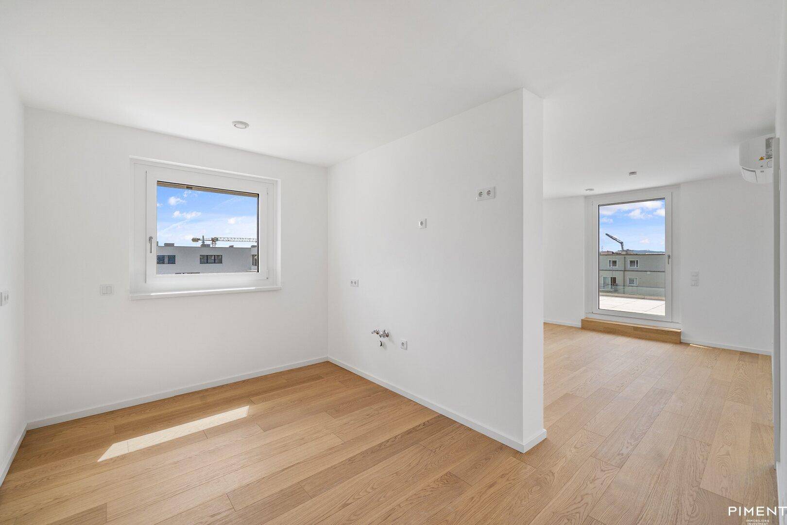 Lichtdurchfluteter, unmöblierter Raum mit Holzboden und einem Fenster, das den Blick nach draußen freigibt.
