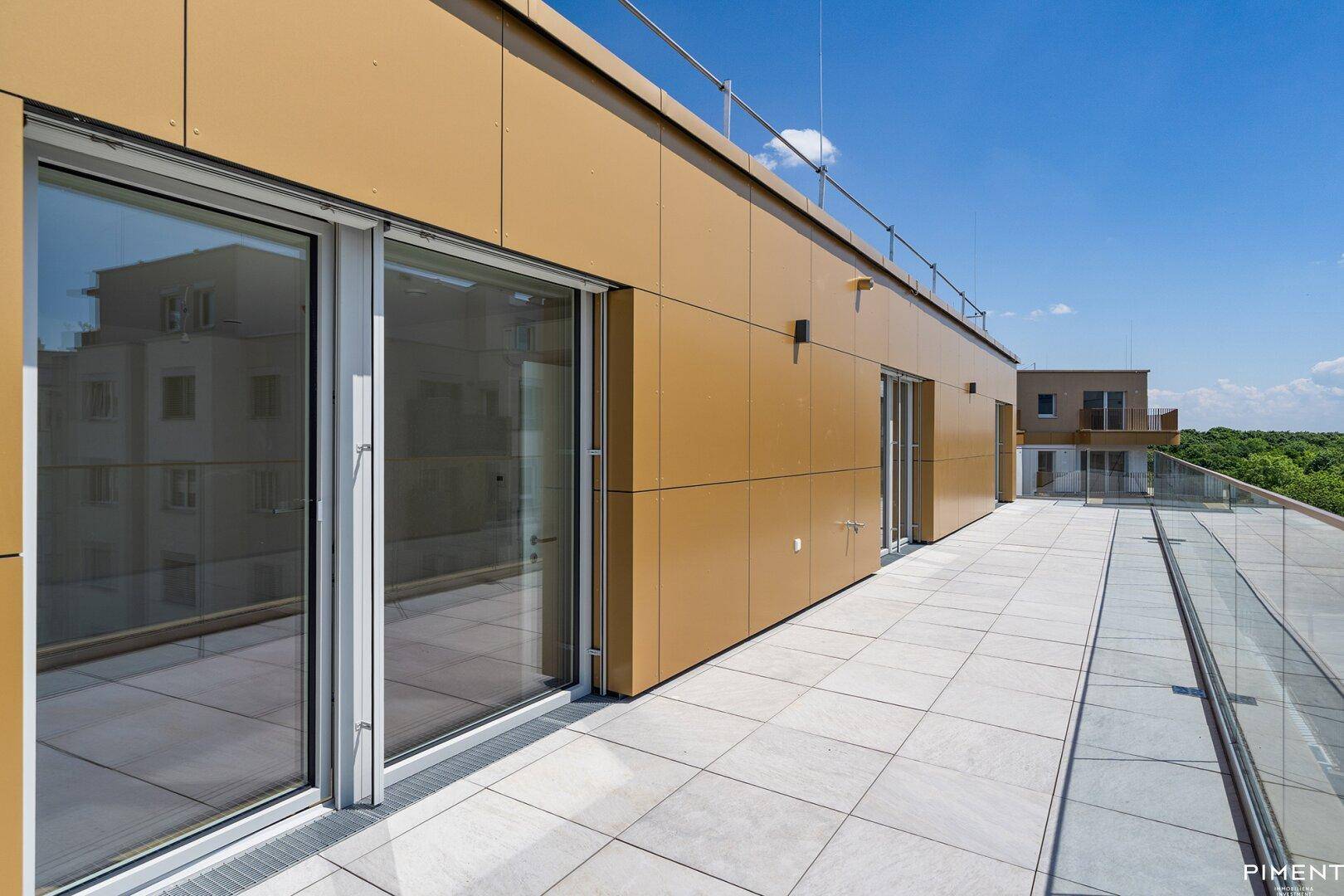 Geräumige Dachterrasse mit Fliesenboden und Glasgeländer, ideal für Entspannung im Freien und Weitblick.