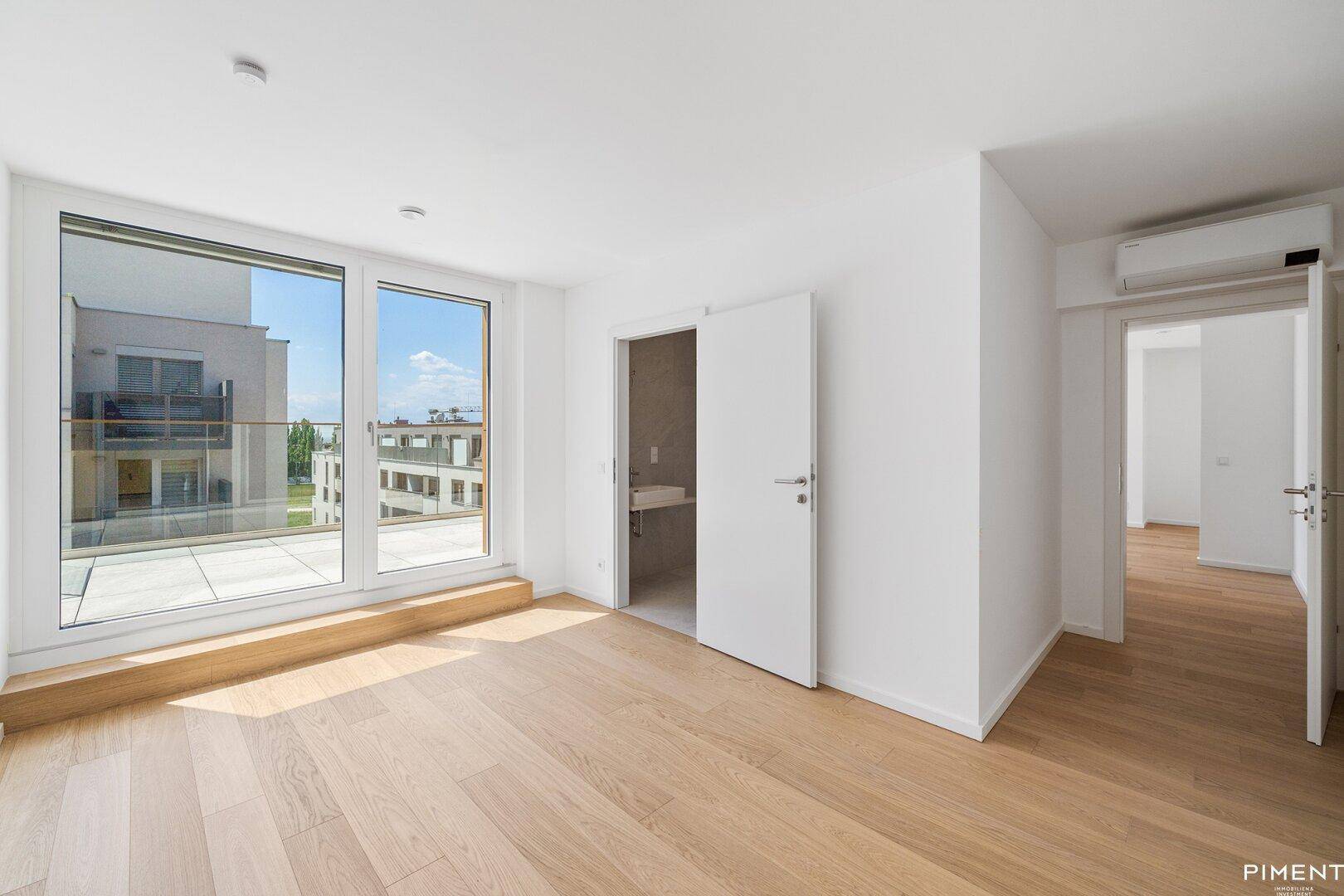 Heller Raum mit Holzboden und Zugang zu einem modernen Badezimmer, ideal für ein Schlaf- oder Wohnzimmer.