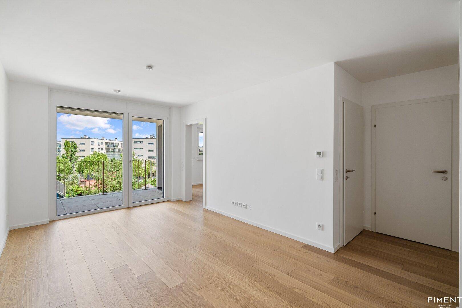 Geräumiges, helles Wohnzimmer mit Eichenparkett und Zugang zu einem Balkon.