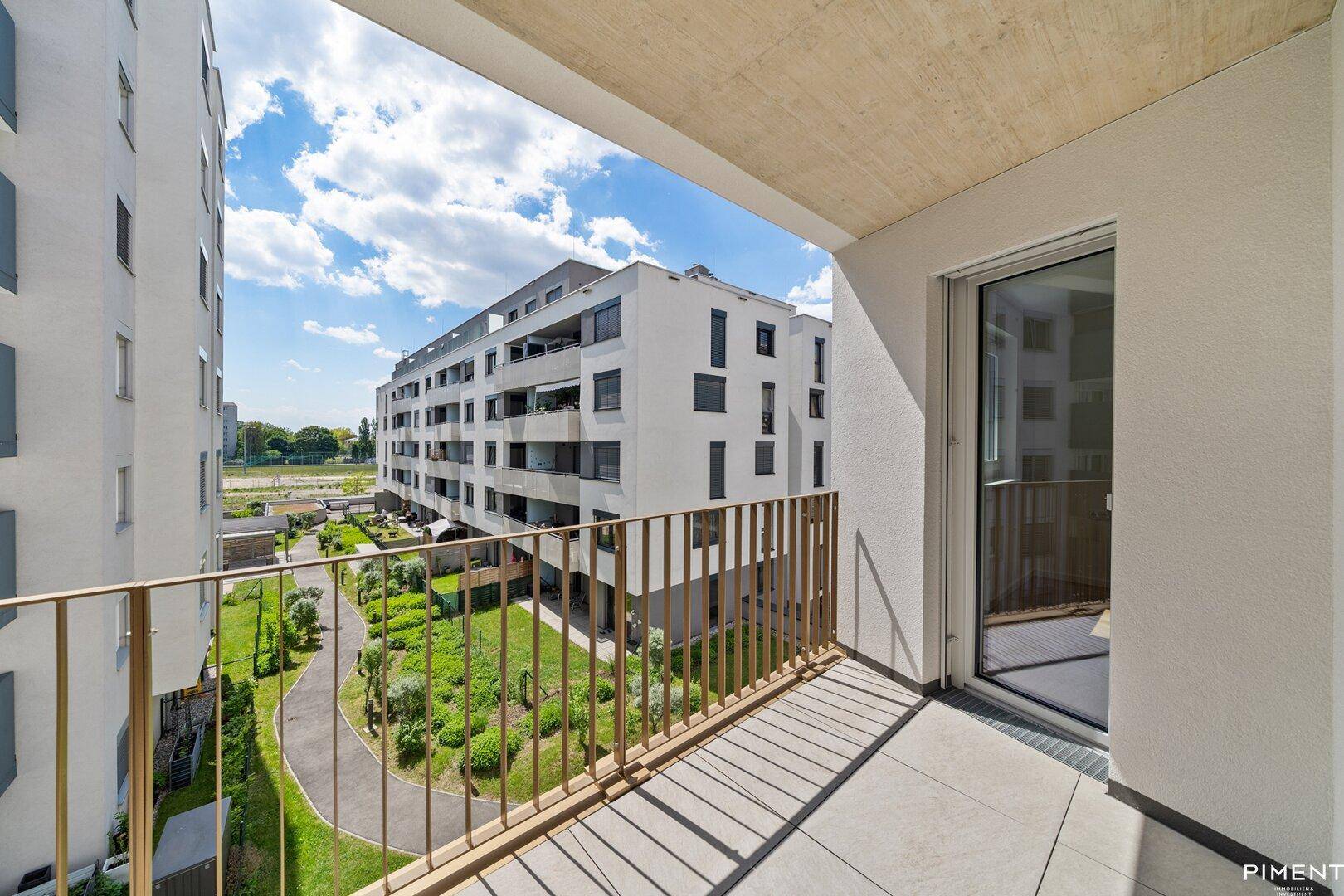 Heller Balkon mit Blick auf die umliegenden modernen Gebäude und die grüne Anlage.