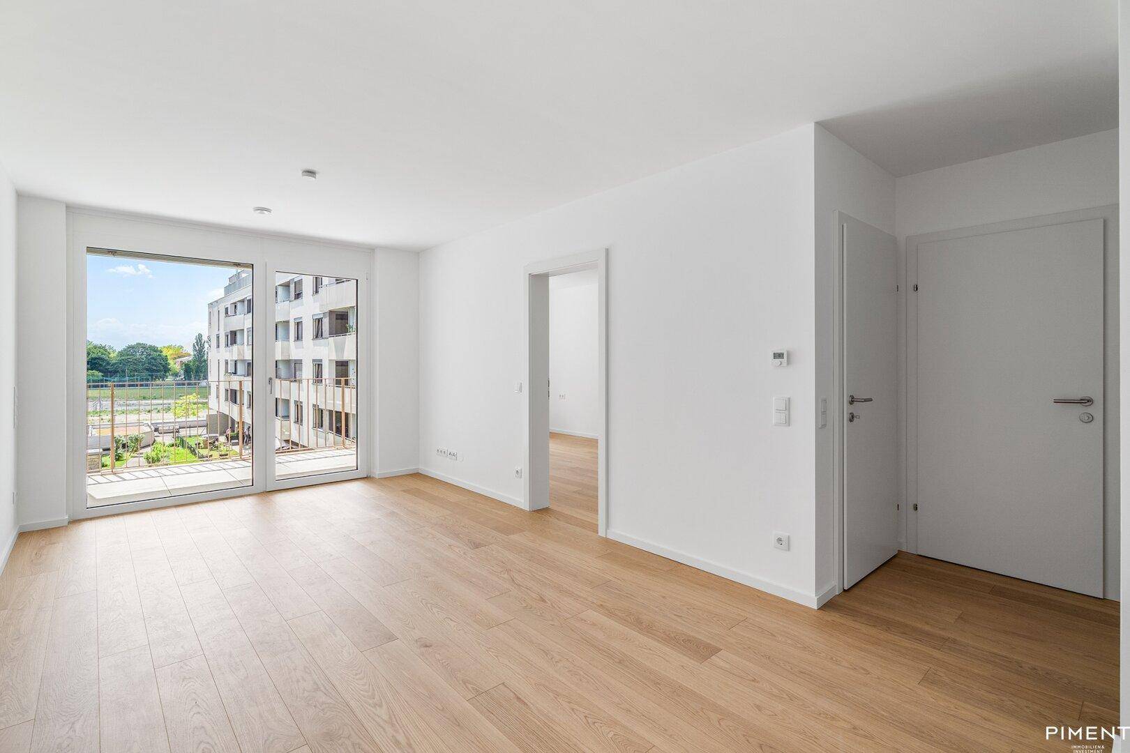 Geräumiges, helles Wohnzimmer mit Eichenparkett und Zugang zu einem Balkon oder einer Terrasse.