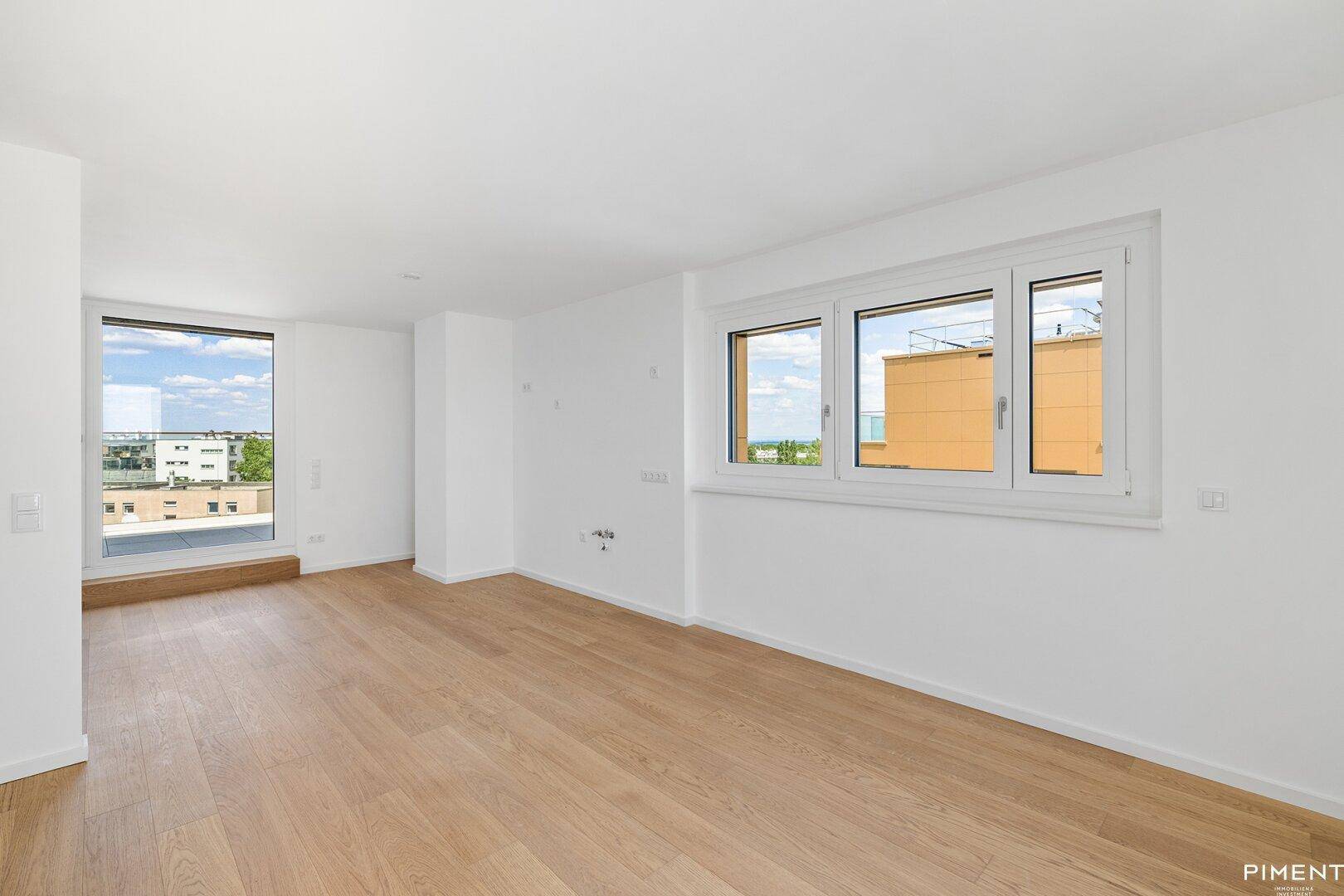 Helles, leeres Zimmer mit großen Fenstern und modernem Holzparkettboden, bereit zur Einrichtung.