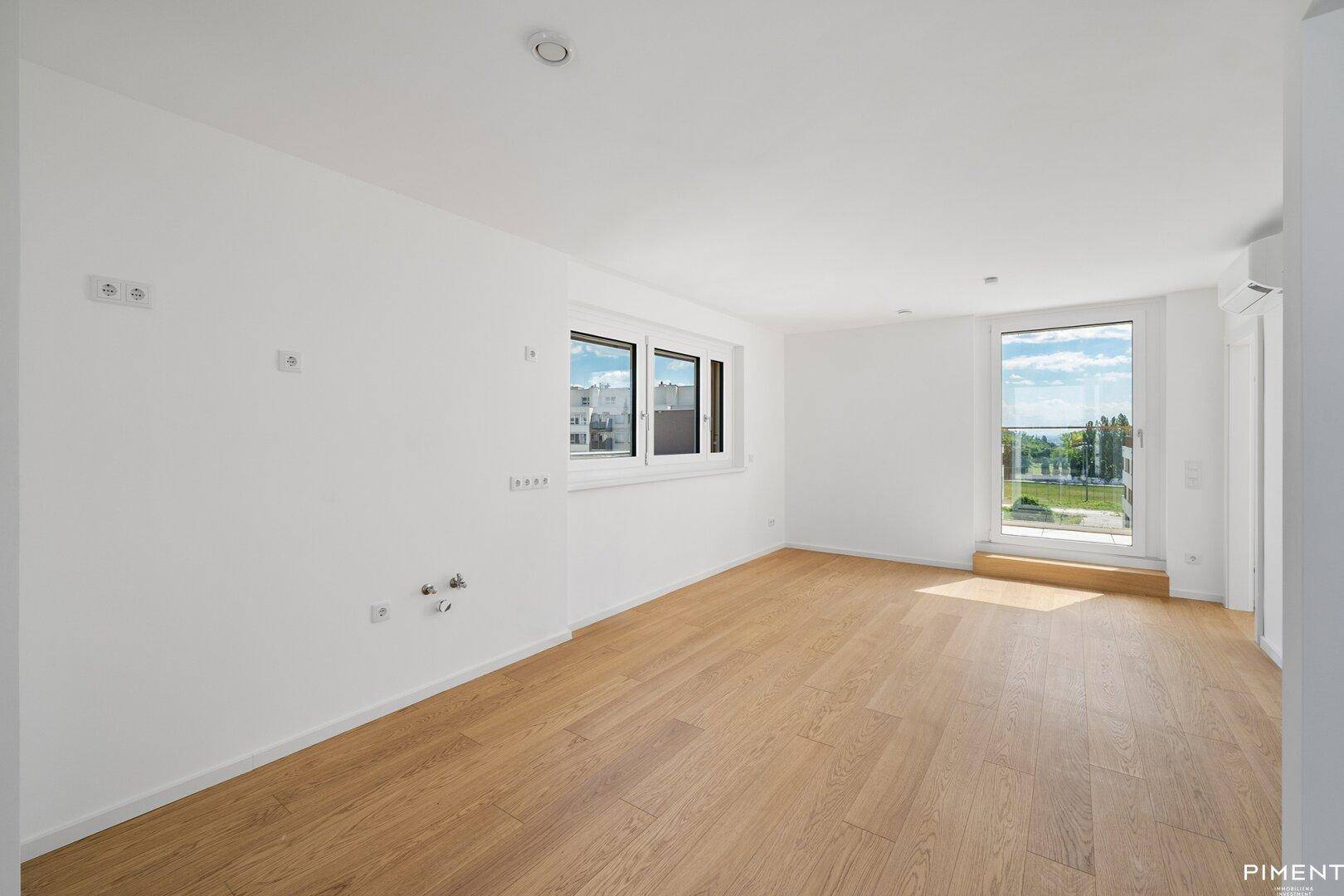 Lichtdurchfluteter Raum mit Eichenparkett und Zugang zu einem Balkon oder einer Terrasse.