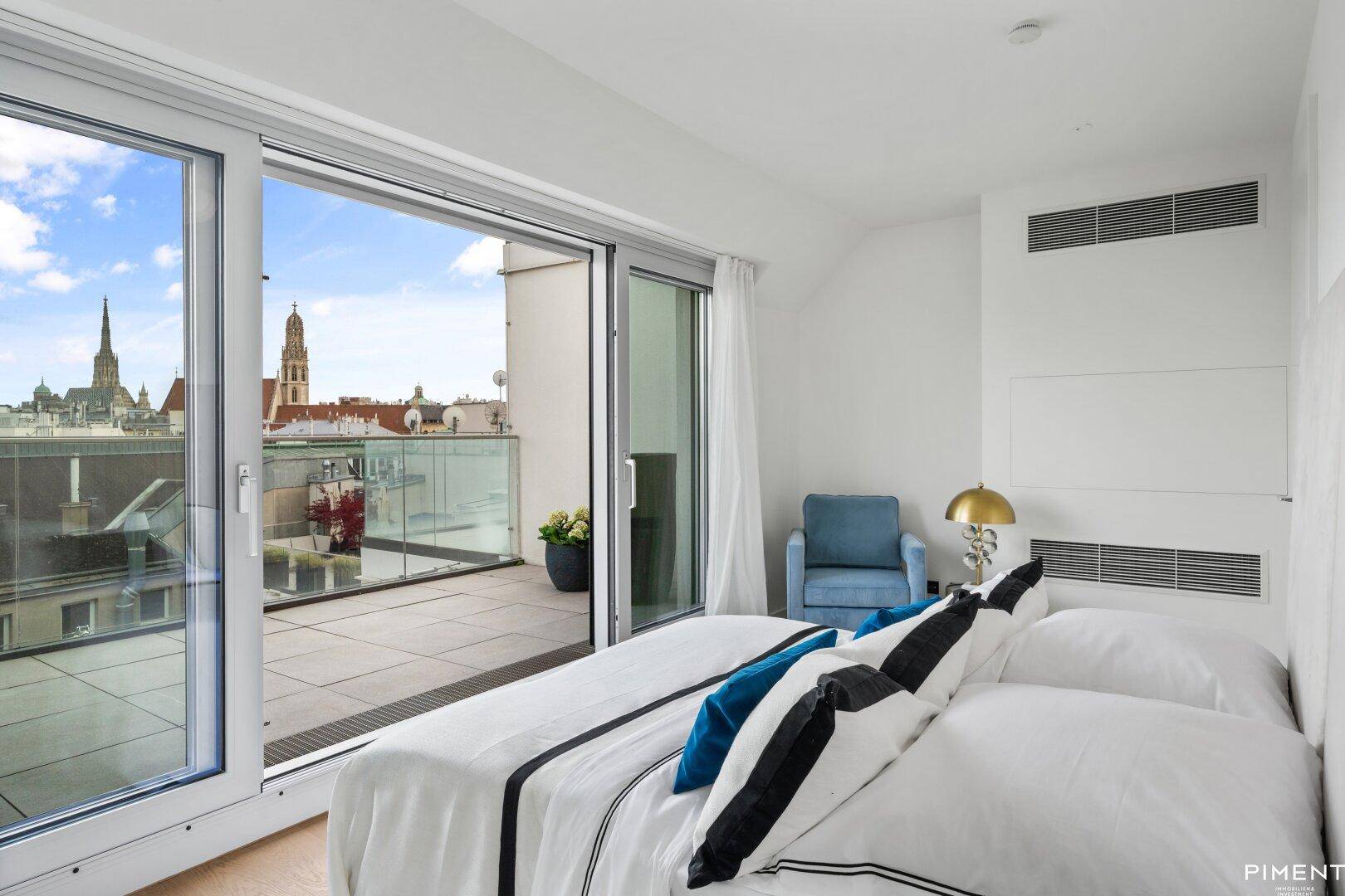 Schlafzimmer mit direktem Zugang zur Terrasse und Panoramablick über die Dächer der Stadt.