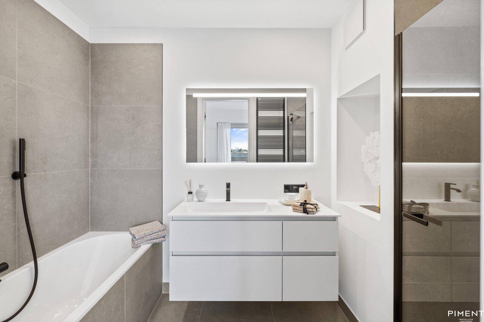 Modernes Badezimmer mit Badewanne, Duschbereich und stilvollem Waschtisch mit Spiegel.