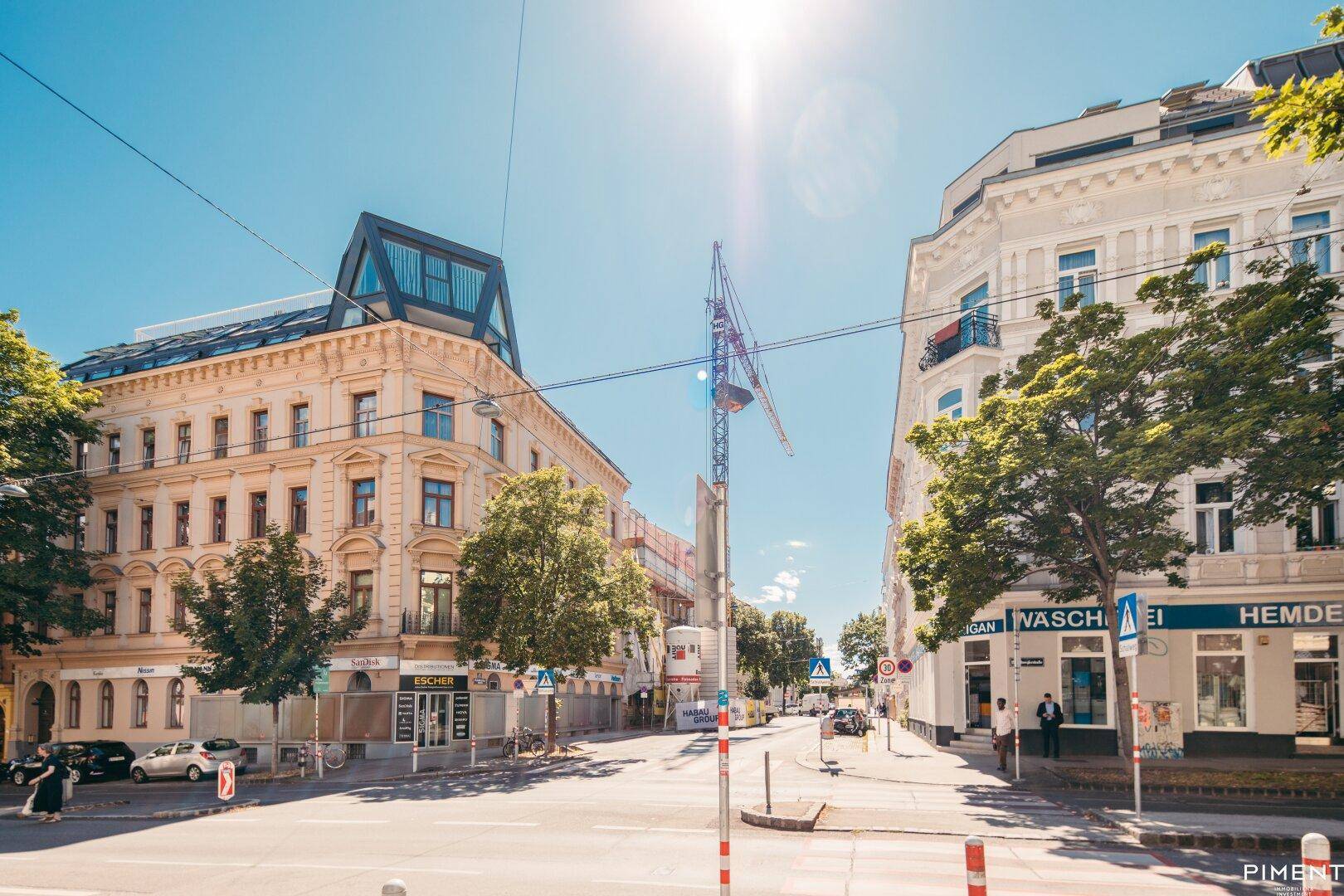 Sonnige Stadtansicht mit historischen Gebäuden, Bäumen und einem Baukran.