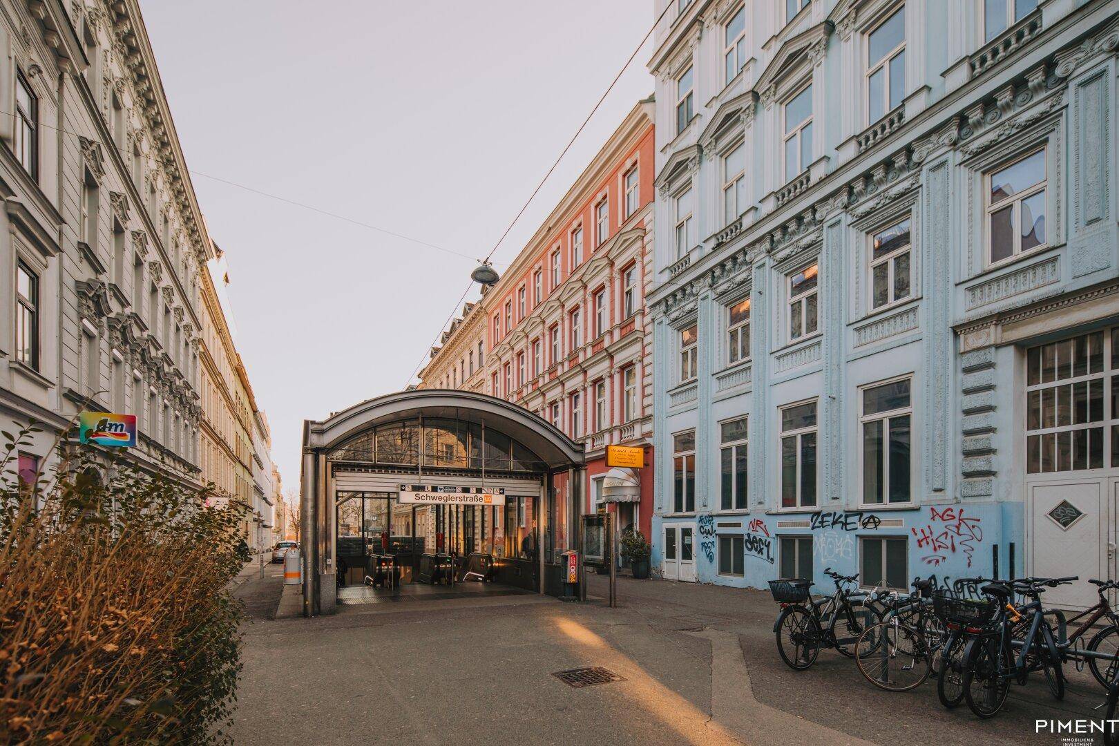 Historische Gebäude und ein U-Bahn-Eingang in einer belebten Stadtstraße.