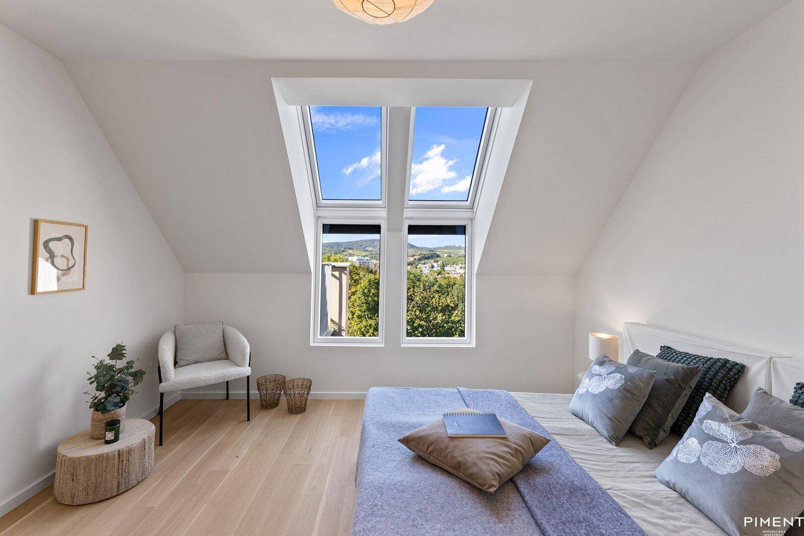 Gemütliches Schlafzimmer im Dachgeschoss mit Holzboden und großen Dachfenstern mit Weitblick.