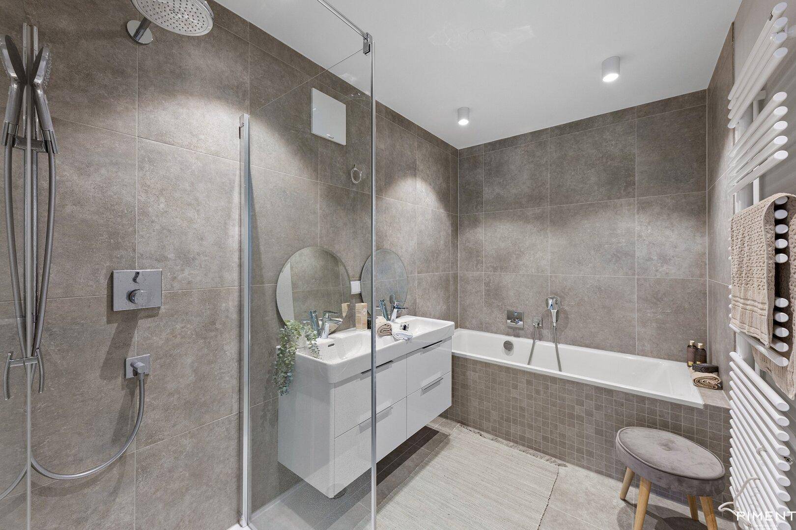 Modernes Badezimmer mit Doppelwaschbecken, Badewanne, Dusche und beheiztem Handtuchhalter.