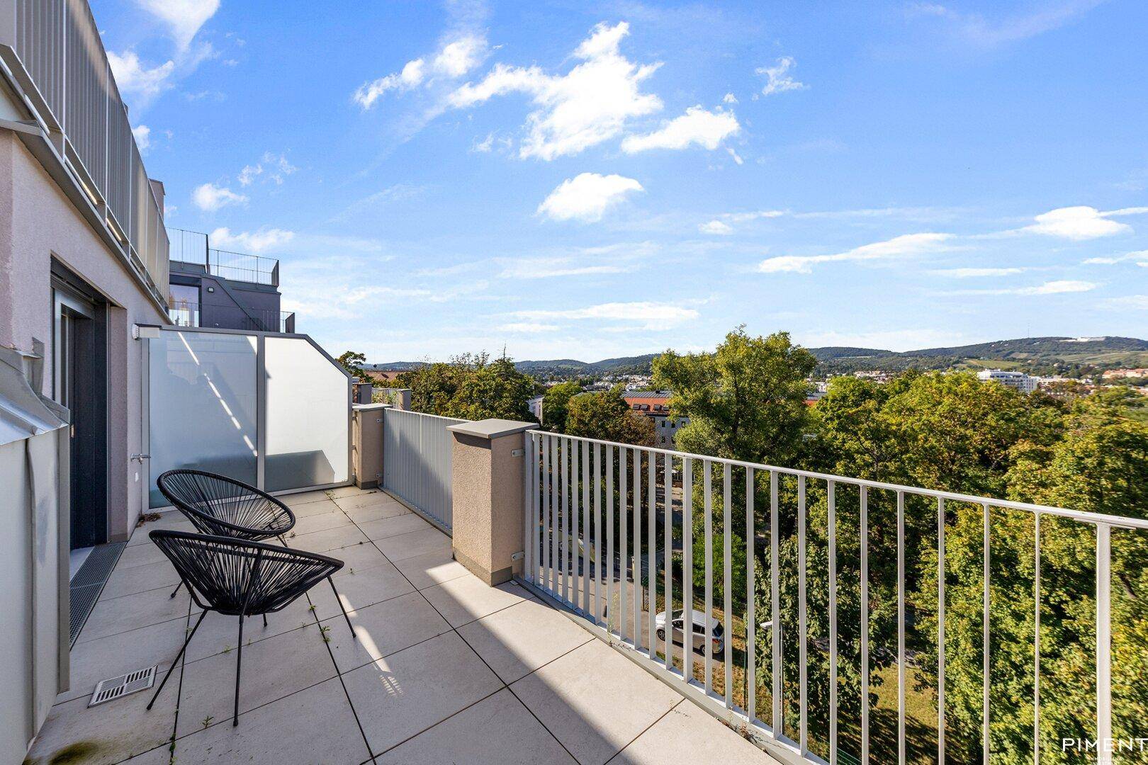 Geräumiger Balkon mit Fliesenboden, Sitzgelegenheiten und weitem Blick über die Landschaft.