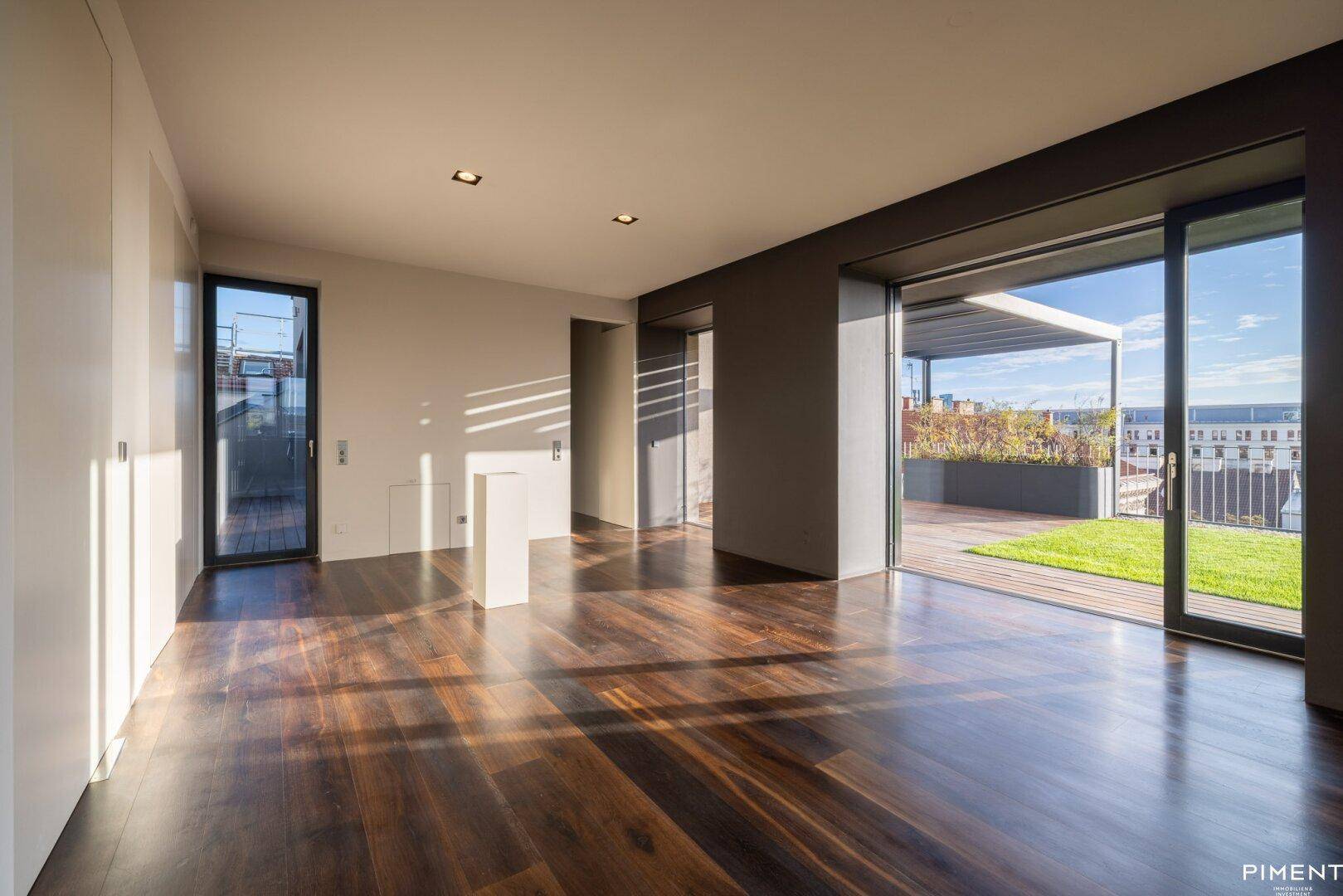 Lichtdurchflutetes Wohnzimmer mit elegantem Holzparkett und direktem Zugang zur großzügigen Dachterrasse.