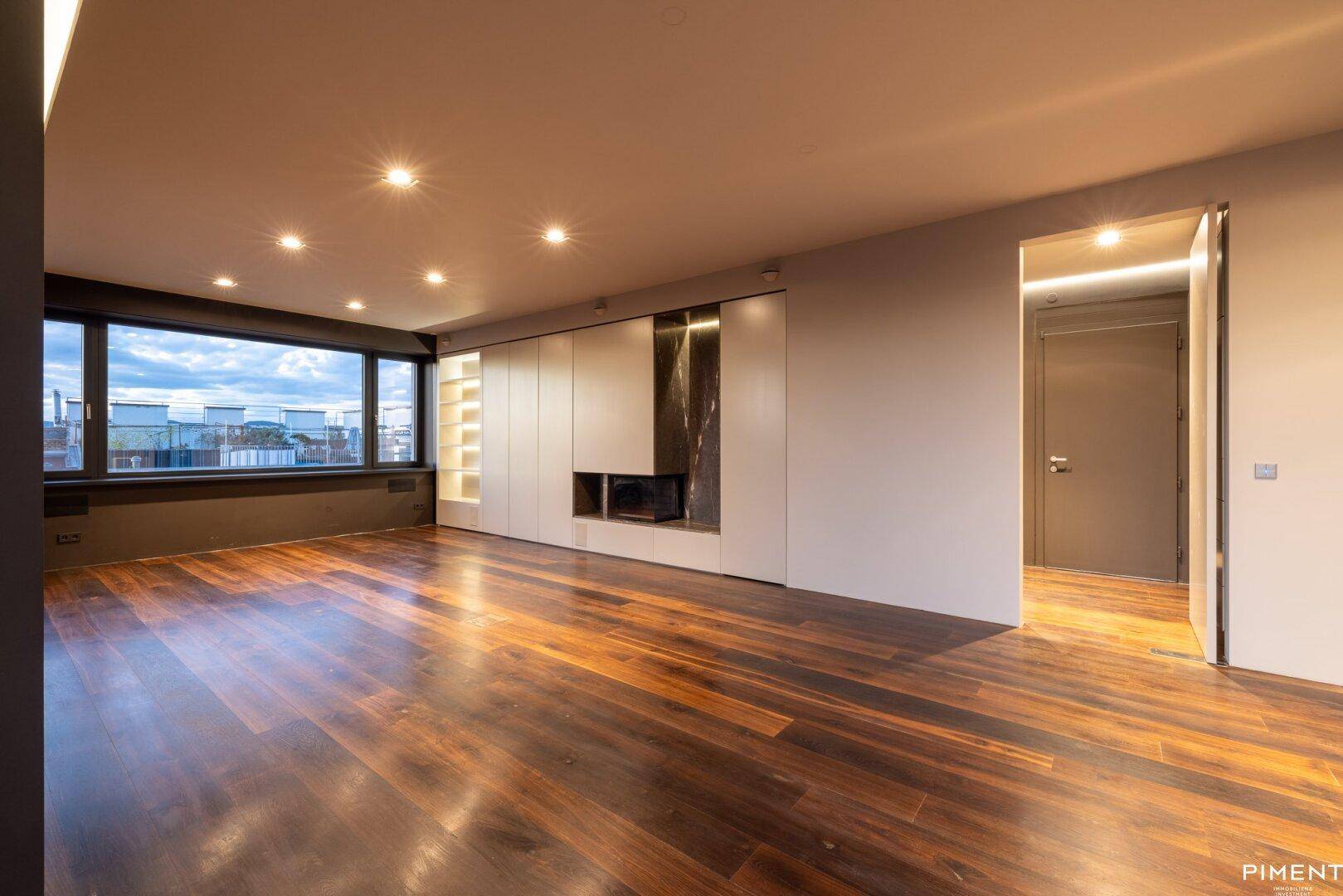 Modernes Wohnzimmer mit dunklem Holzfußboden, Einbauschränken, Kamin und weitem Blick über die Stadt.