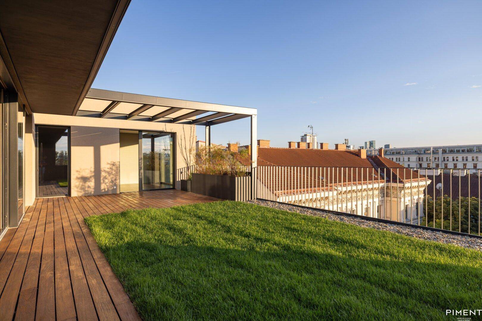 Weitläufige Dachterrasse mit Rasen und Holzdeck, bietet einen weiten Blick über die Stadt.