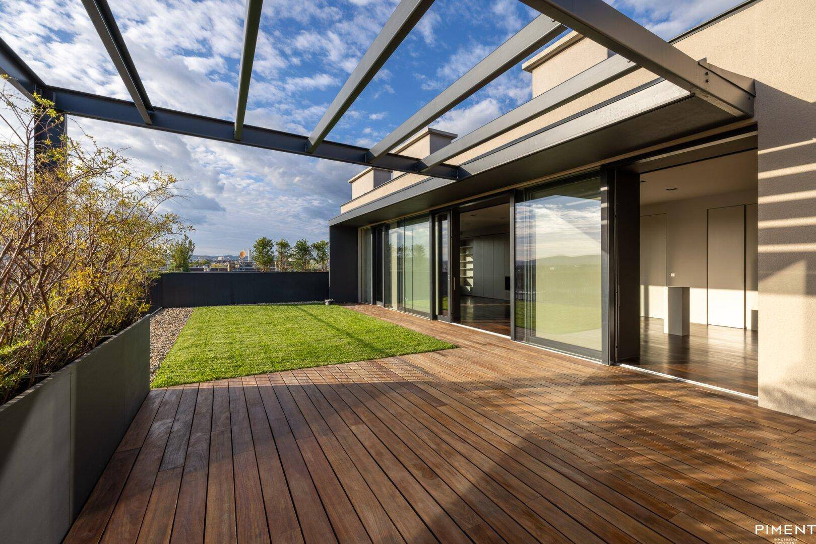 Großzügige Dachterrasse mit Holzdeck, Rasenfläche und moderner Pergola-Struktur.