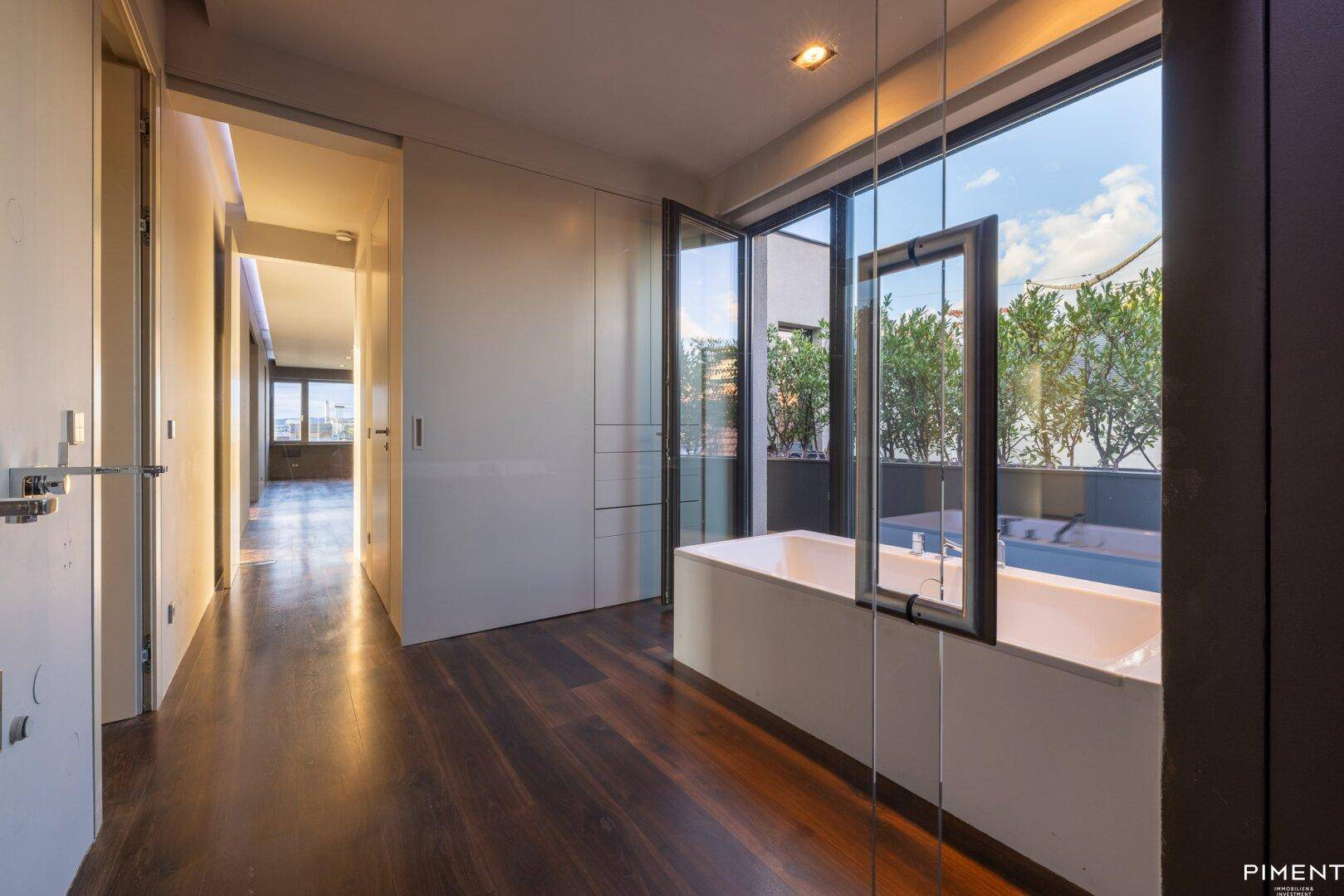 Elegantes Badezimmer mit Badewanne, großer Fensterfront und begehbarer Dusche, bietet einen Blick ins Grüne.