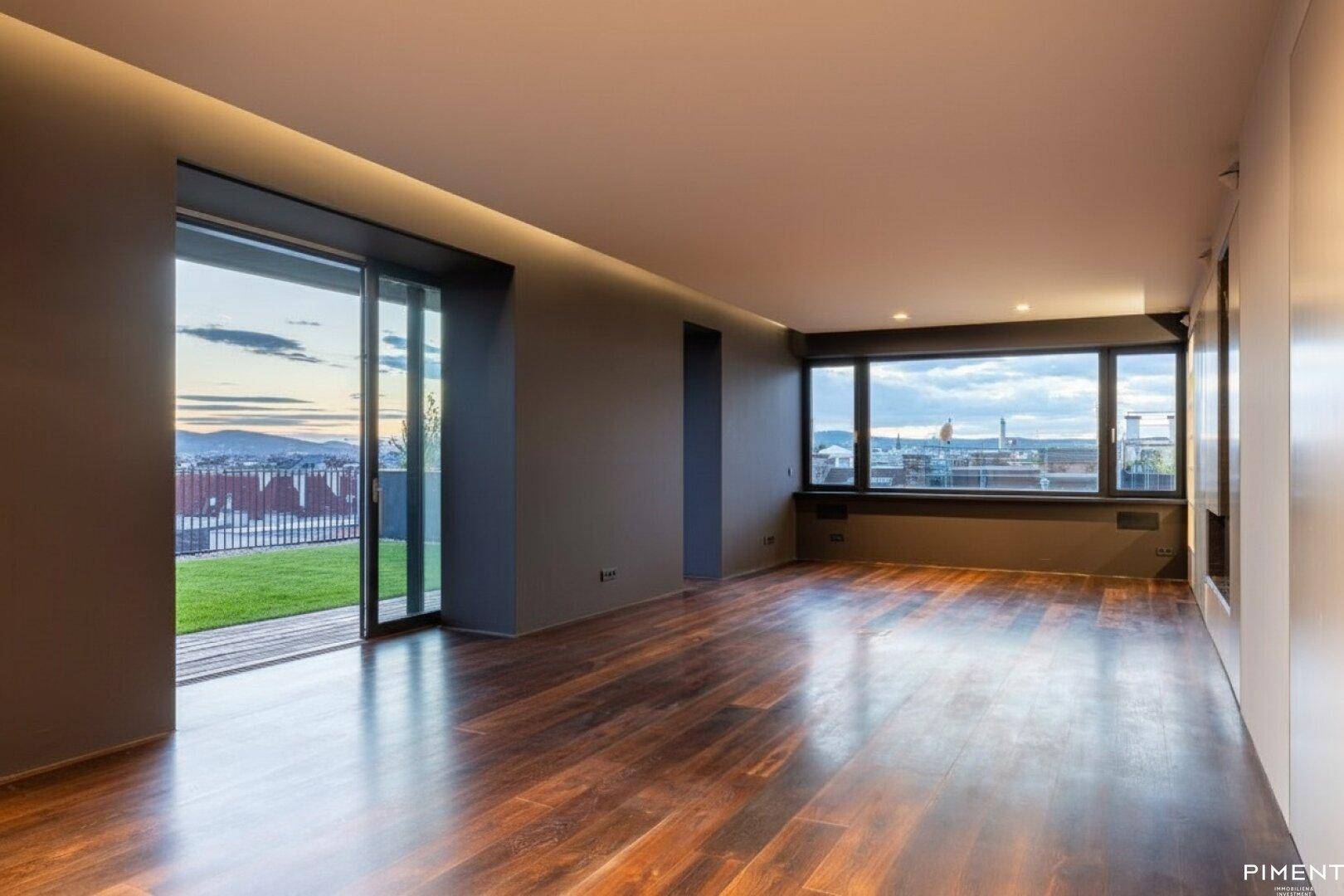 Helles Wohnzimmer mit dunklem Holzfußboden, großen Fenstern und Zugang zur Dachterrasse mit Stadtblick.