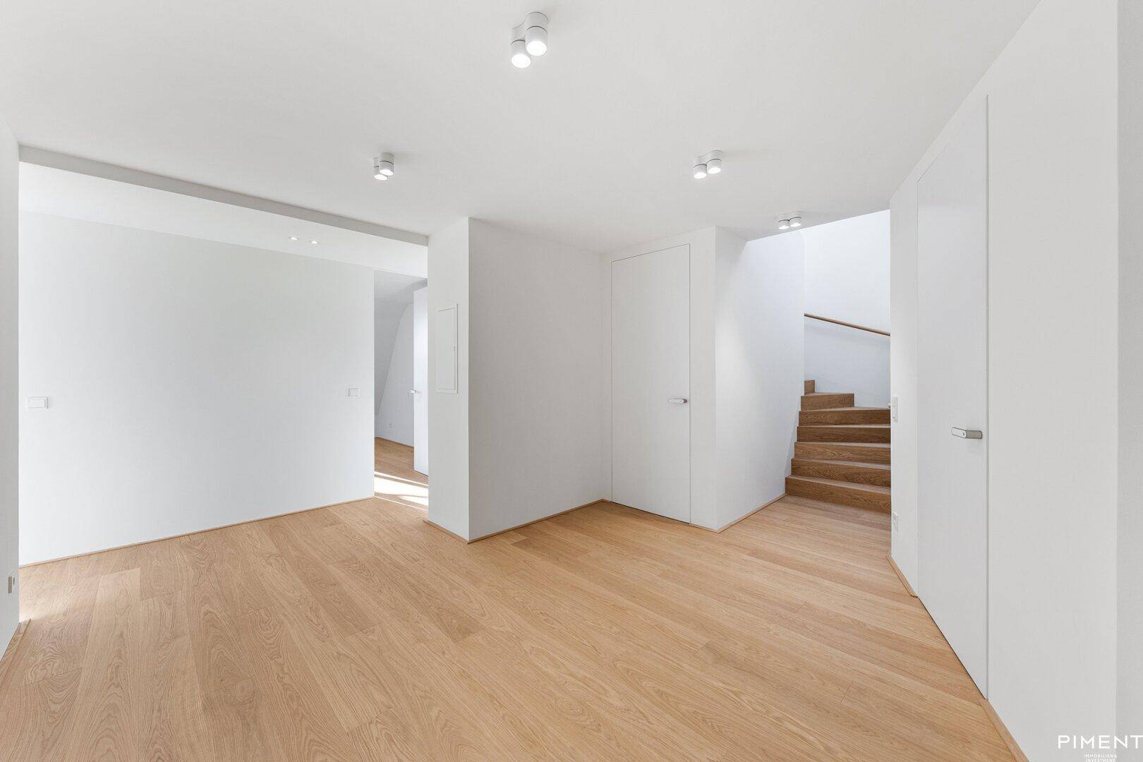 Moderner Eingangsbereich mit Holzboden und offener Holztreppe.