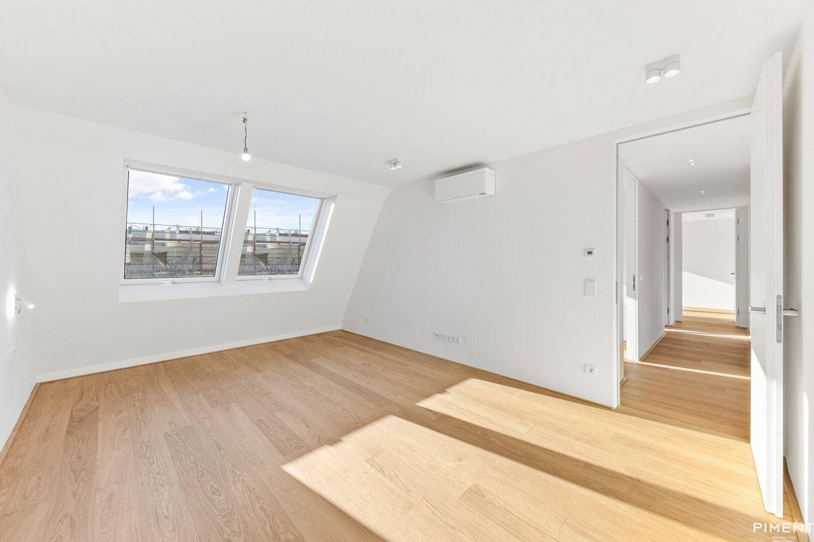 Helles Schlafzimmer mit Holzboden, Dachschräge und Blick ins Grüne.