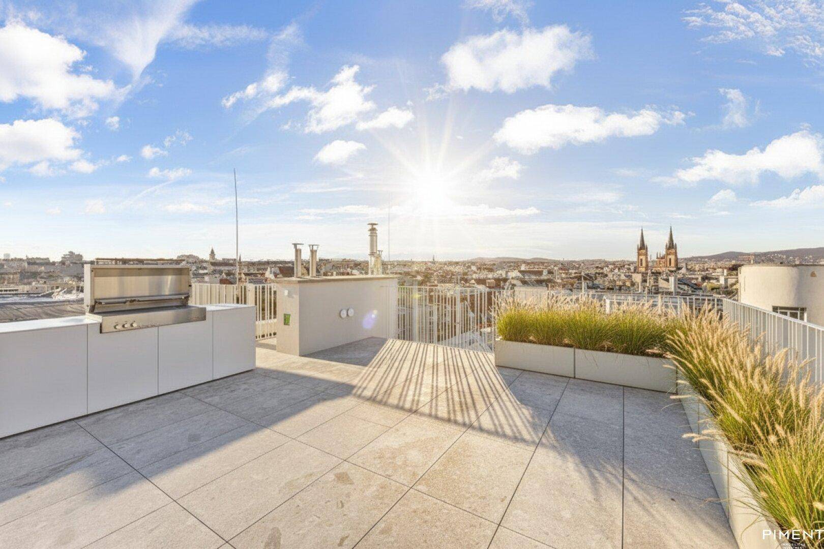 Sonniger Dachgarten mit Außenküche, Grillbereich und weitem Stadtblick.