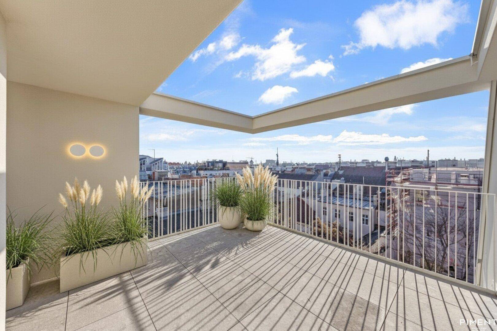 Geräumige Dachterrasse mit Stadtblick und modernen Pflanzenkübeln.