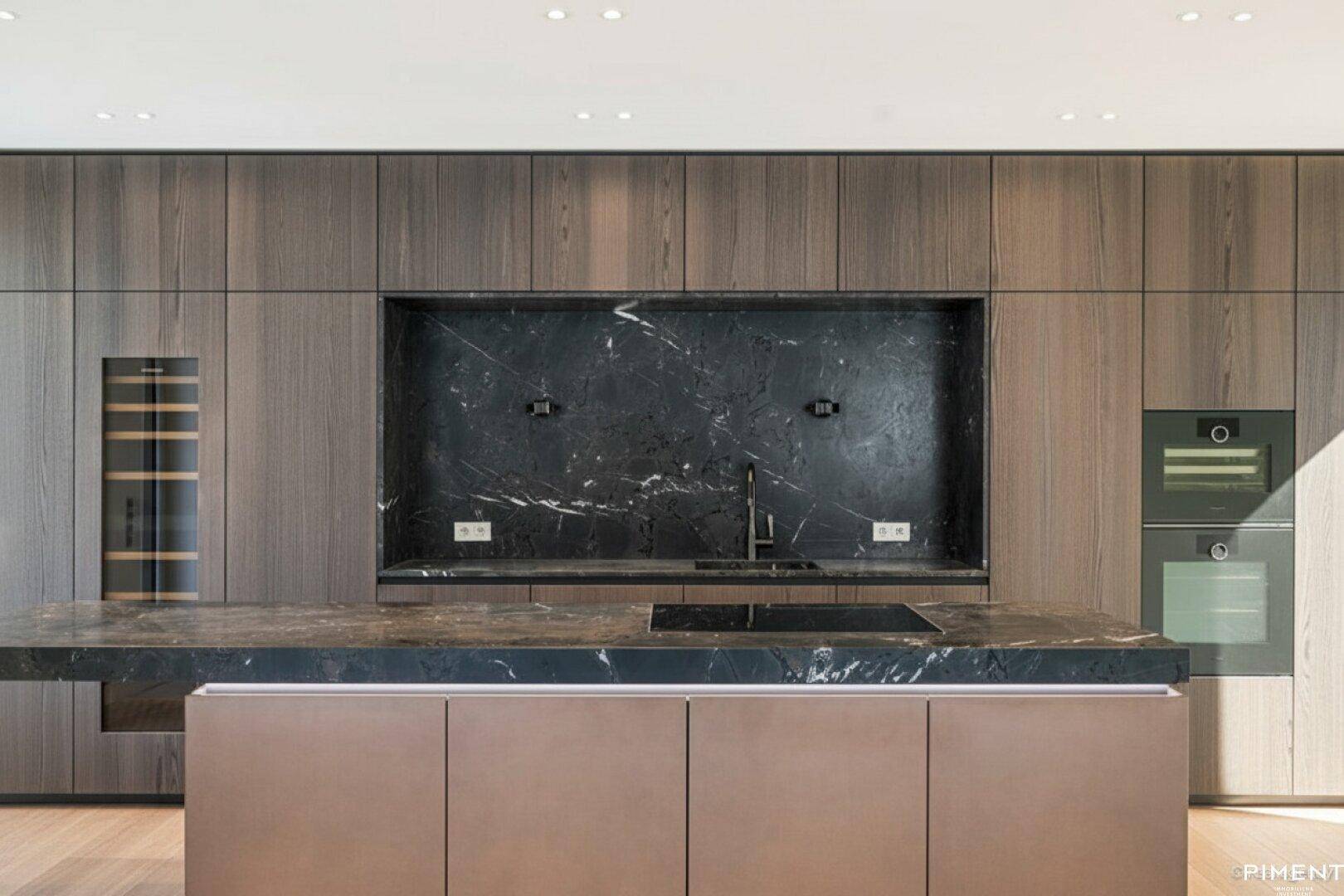 Elegante Küche mit dunklen Holzschränken, Marmorinsel und integrierten Premium-Geräten.
